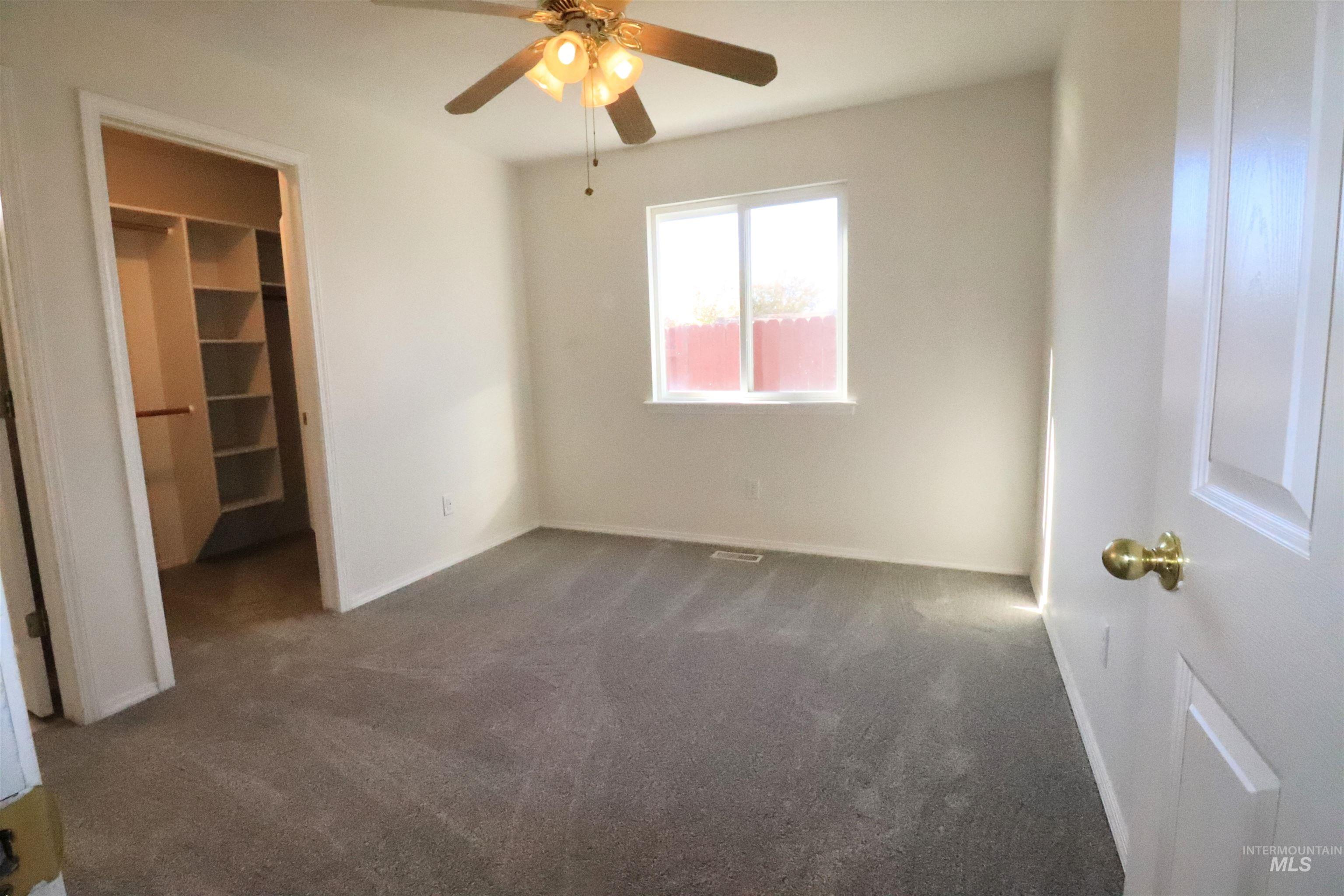 Unfurnished bedroom with carpet floors, a ceiling fan, and a walk in closet