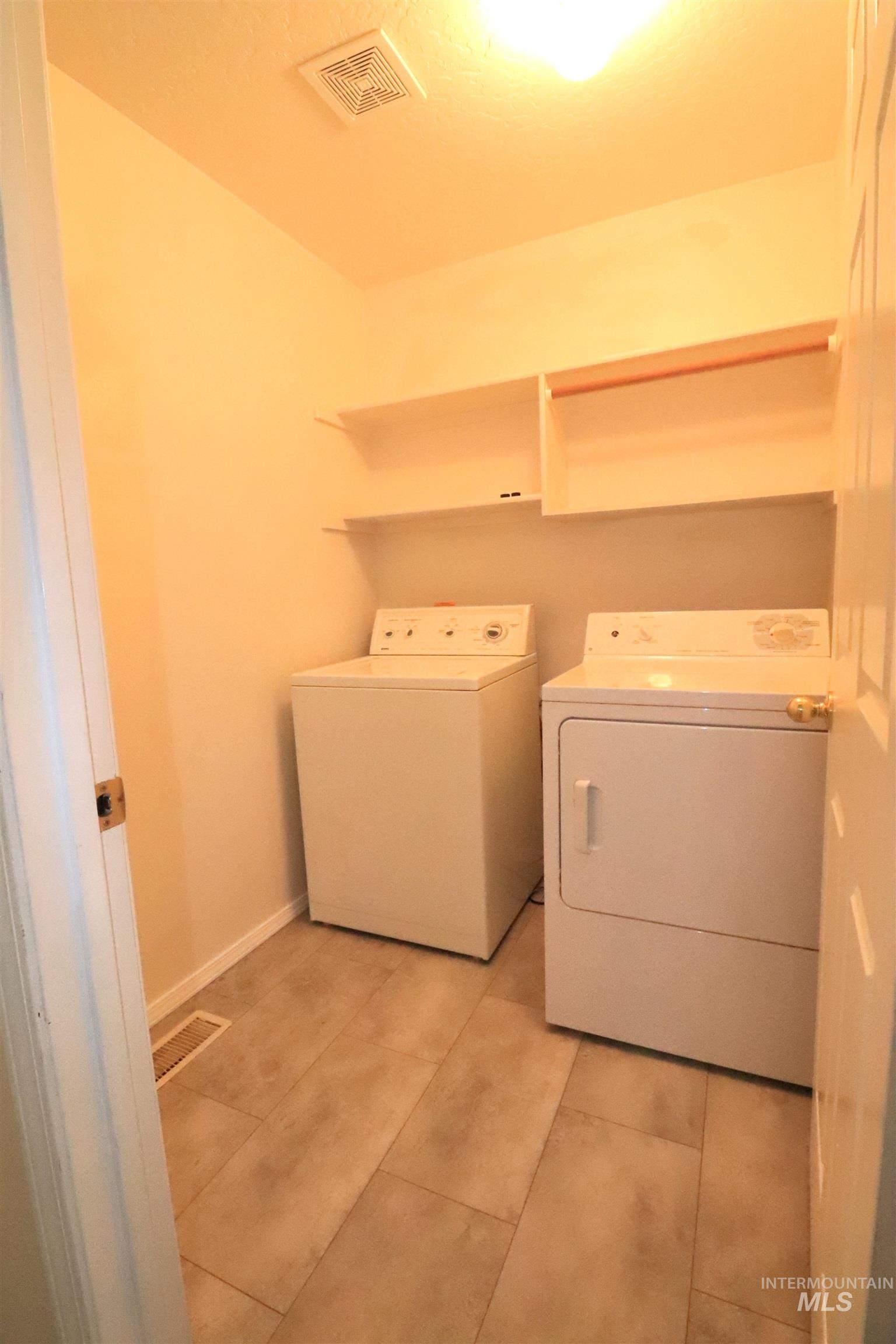 Washroom with independent washer and dryer and light tile patterned floors