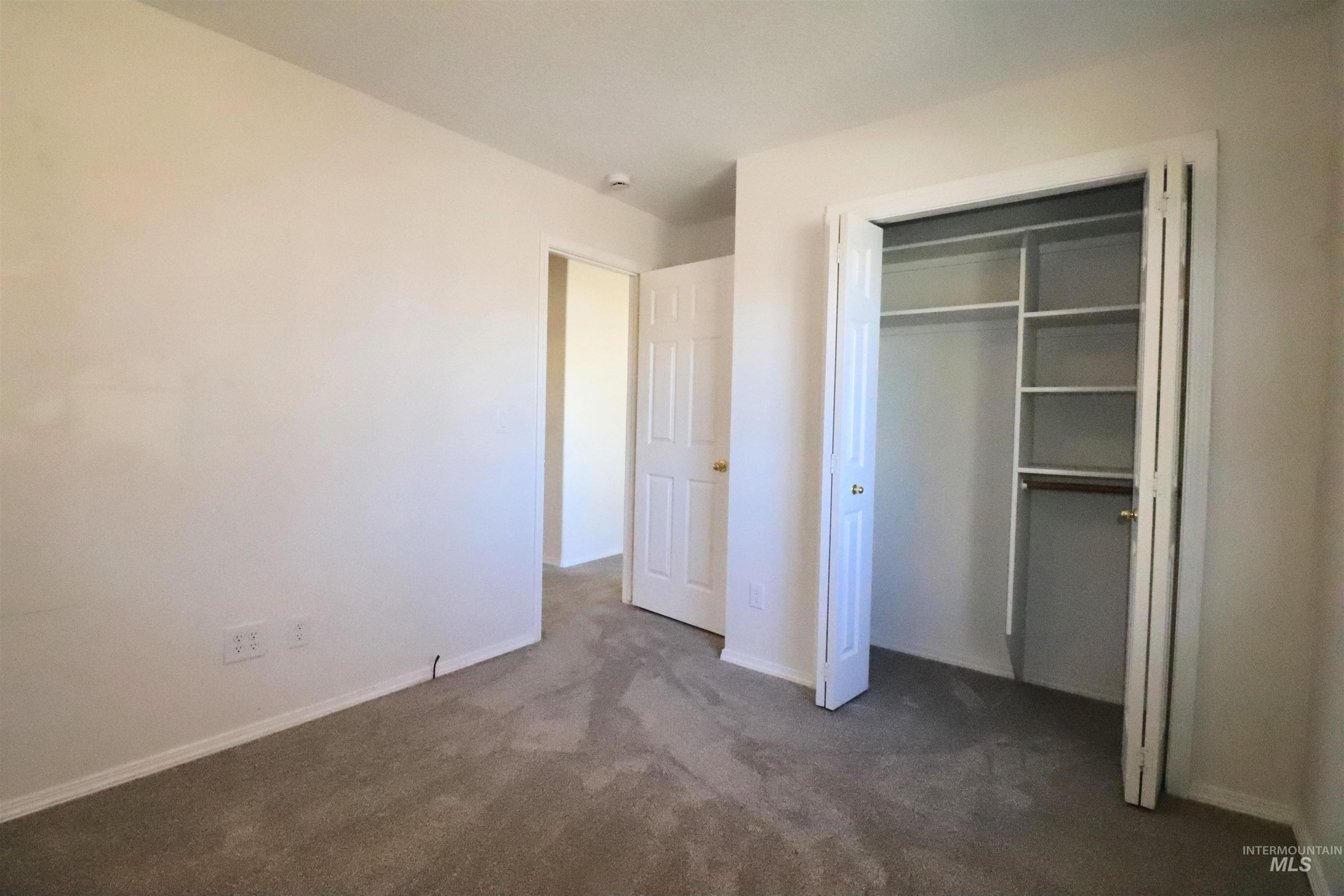 Unfurnished bedroom featuring dark colored carpet and a closet