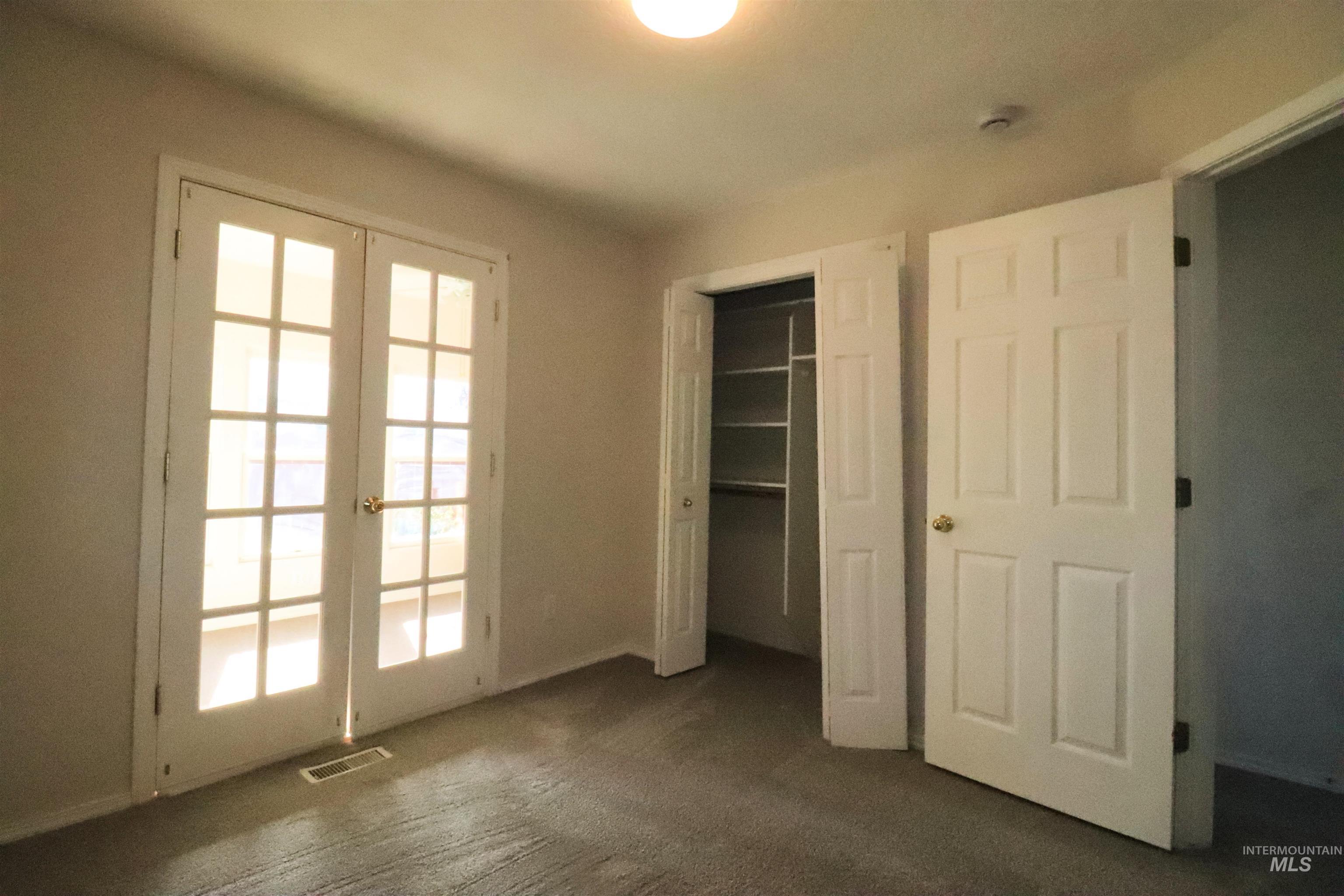 Unfurnished bedroom featuring french doors, a closet, and dark colored carpet