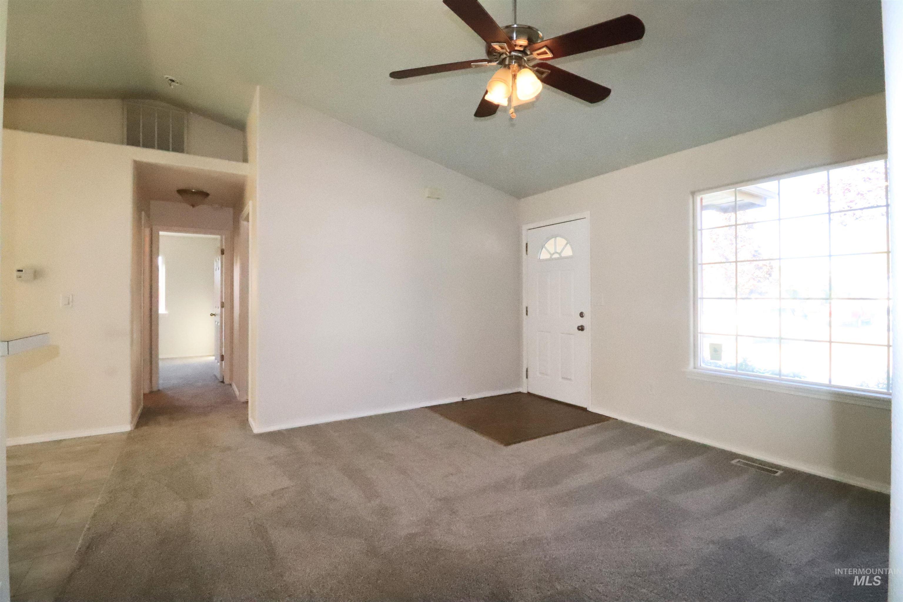 Carpeted entryway with vaulted ceiling and a ceiling fan
