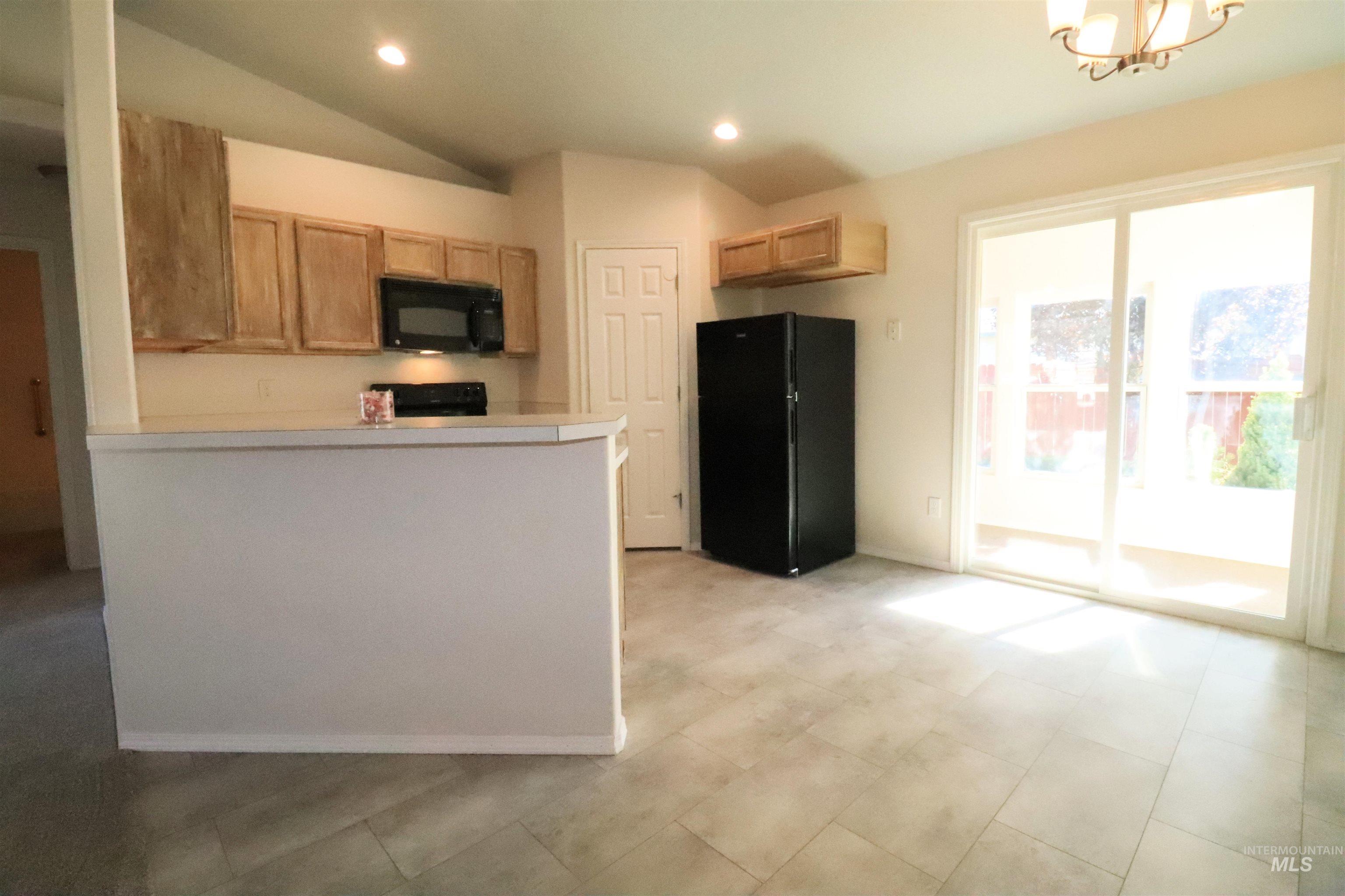 Kitchen with black appliances, light countertops, recessed lighting, vaulted ceiling, and a peninsula