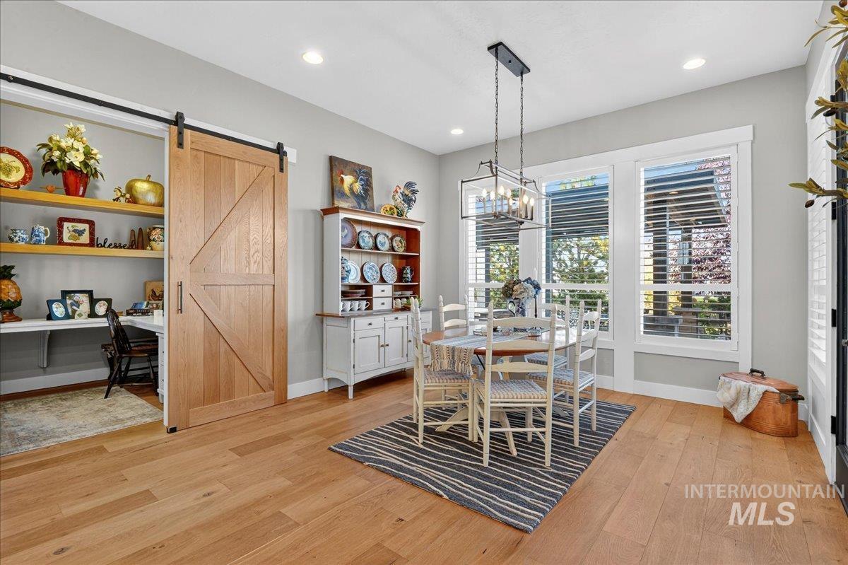 Dining area featuring light wood finished floors, a barn door, recessed lighting, and an office area