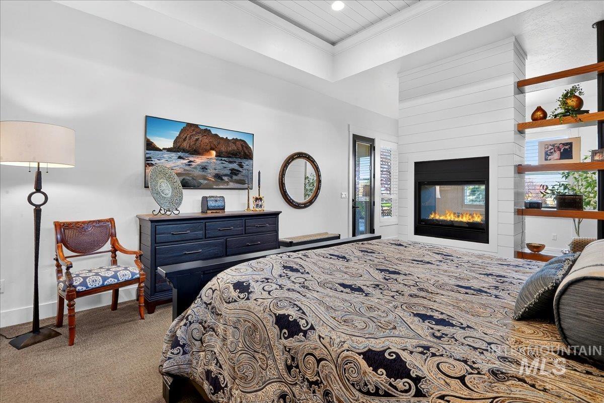 Bedroom featuring ornamental molding, a glass covered fireplace, and carpet floors