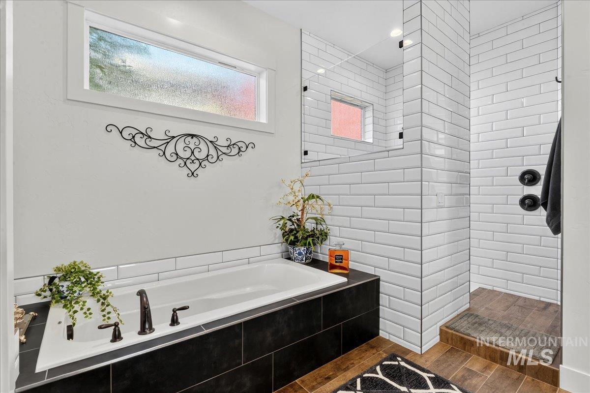 Bathroom with a garden tub, a walk in shower, and dark wood-style floors