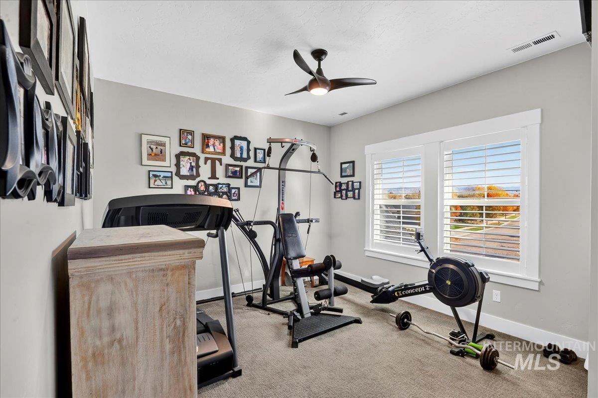 Workout area with carpet floors, a ceiling fan, and a textured ceiling