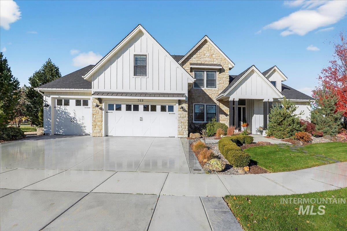 Modern inspired farmhouse featuring board and batten siding, stone siding, and concrete driveway