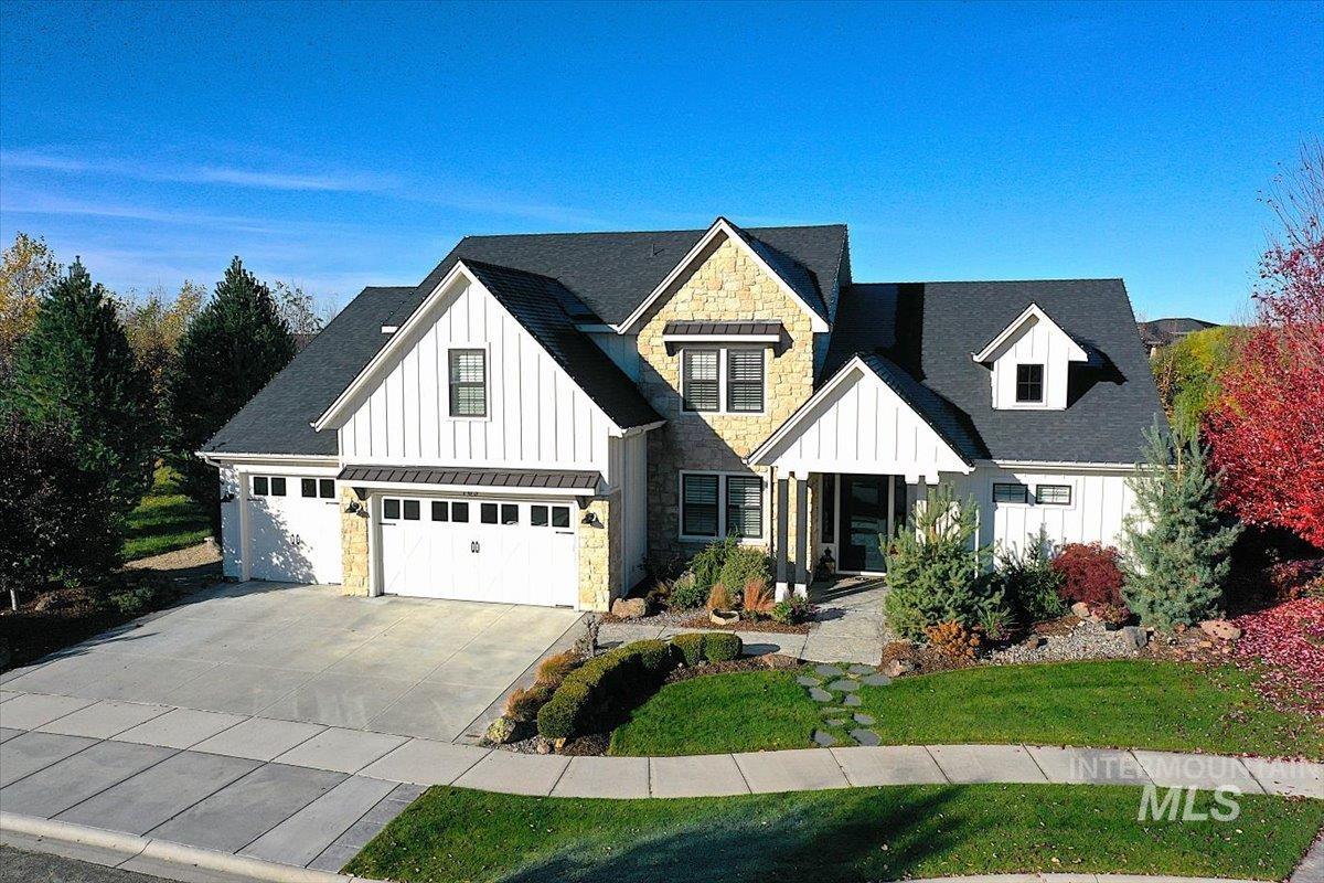 Modern farmhouse style home with board and batten siding, stone siding, concrete driveway, and a front yard