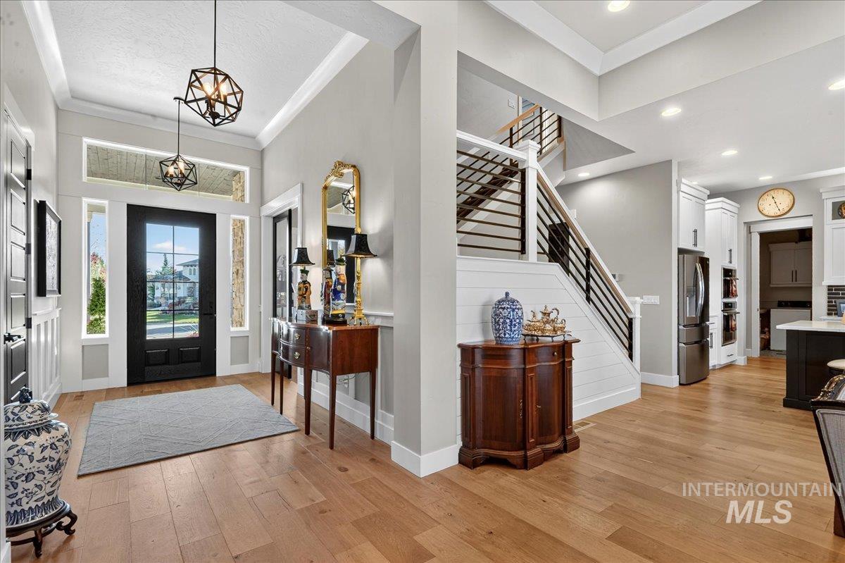 Entryway featuring crown molding, light wood finished floors, stairs, washer / clothes dryer, and a chandelier