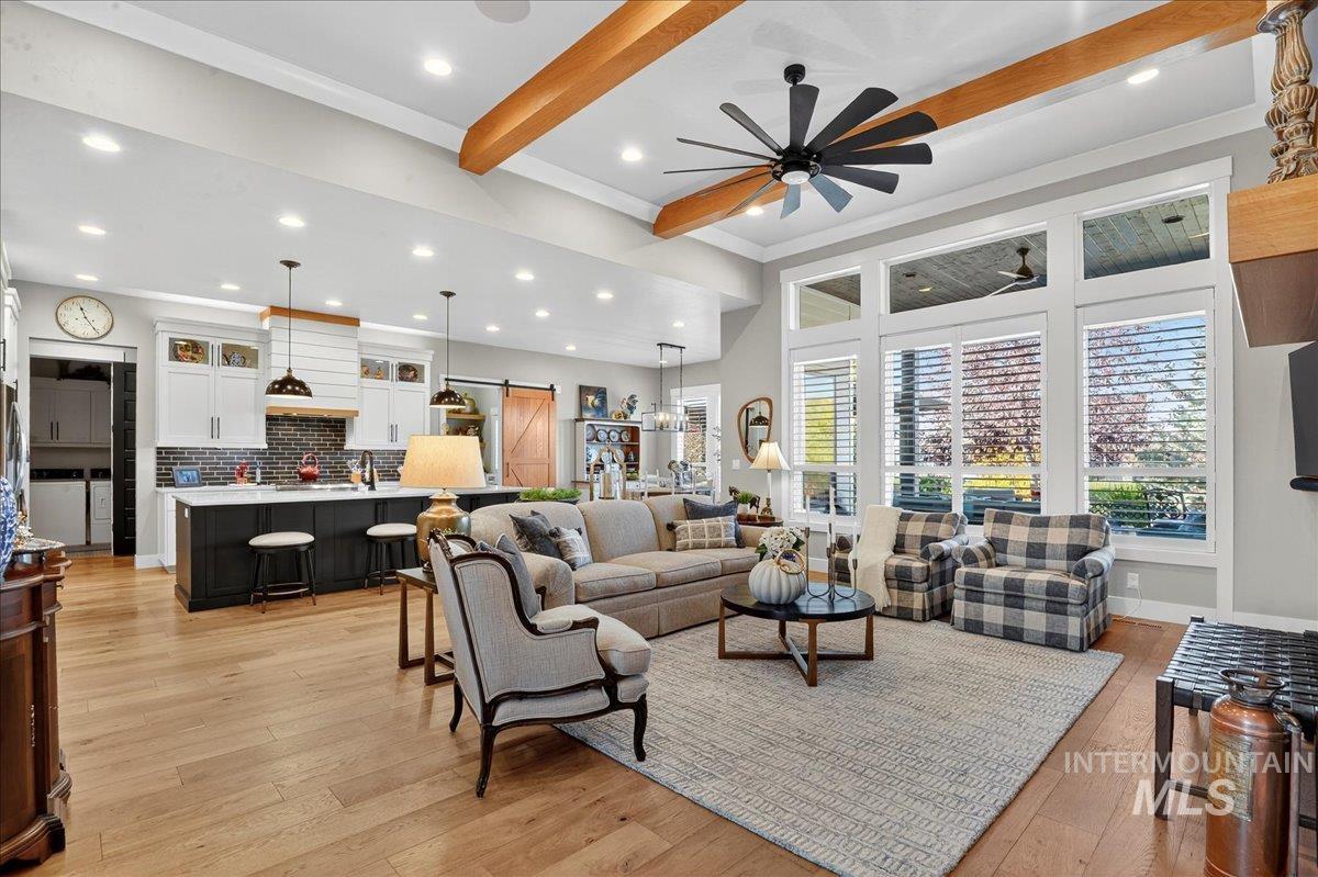 Living room featuring beam ceiling, a barn door, light wood-style flooring, recessed lighting, and ceiling fan
