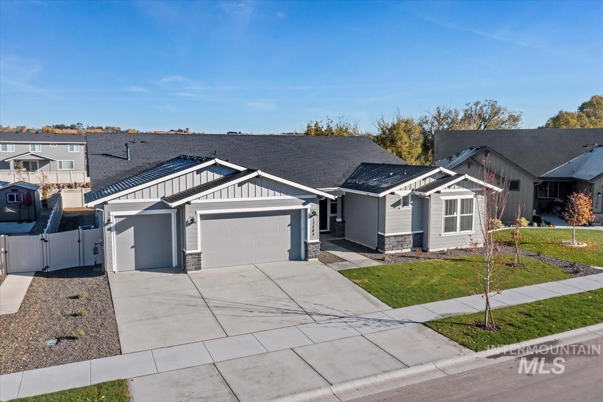 Craftsman house featuring a gate, board and batten siding, a garage, stone siding, and concrete driveway