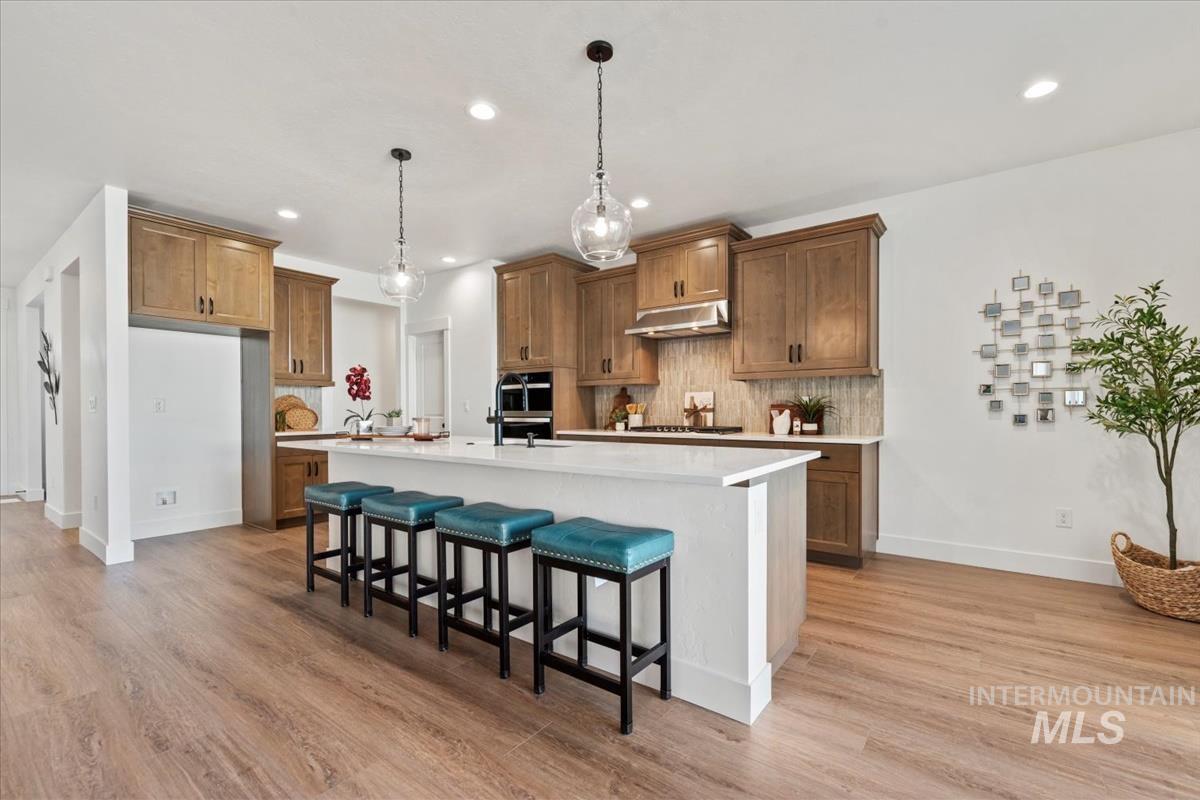 Kitchen with brown cabinets, a kitchen bar, backsplash, and recessed lighting