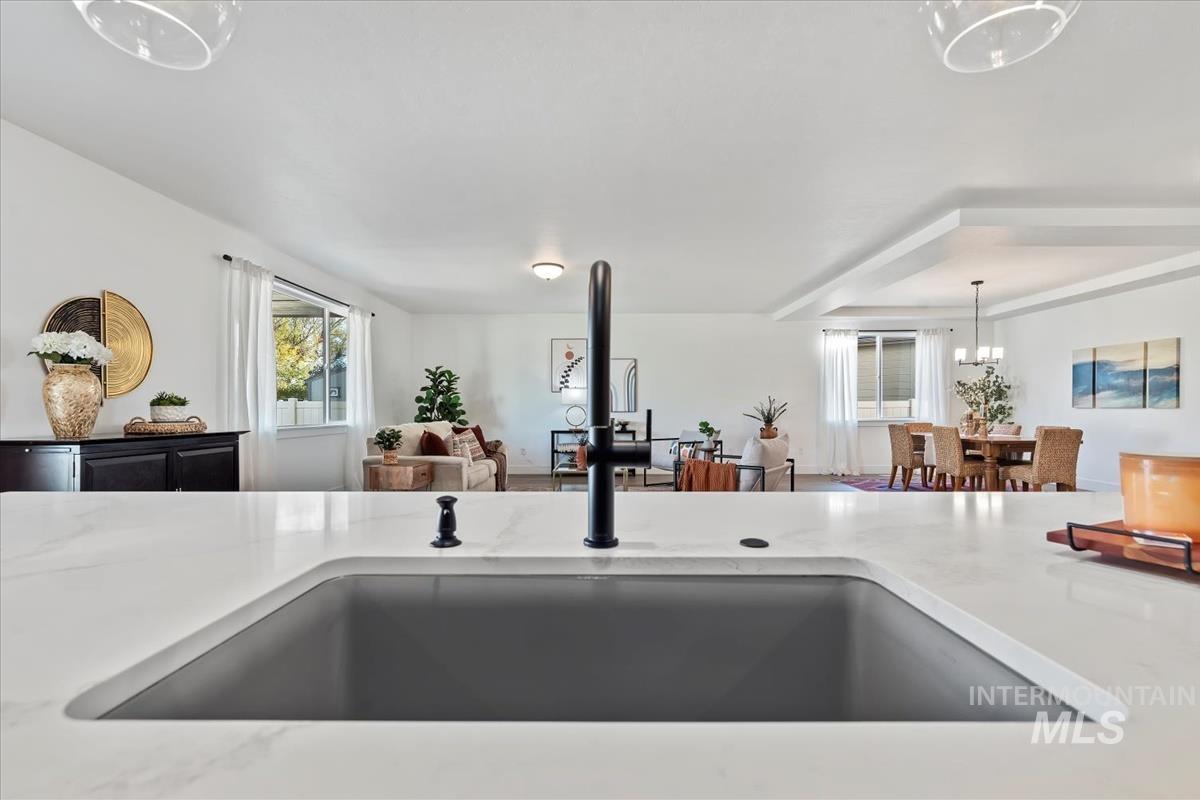 Kitchen view of decorative light fixtures, light stone counters, and a chandelier