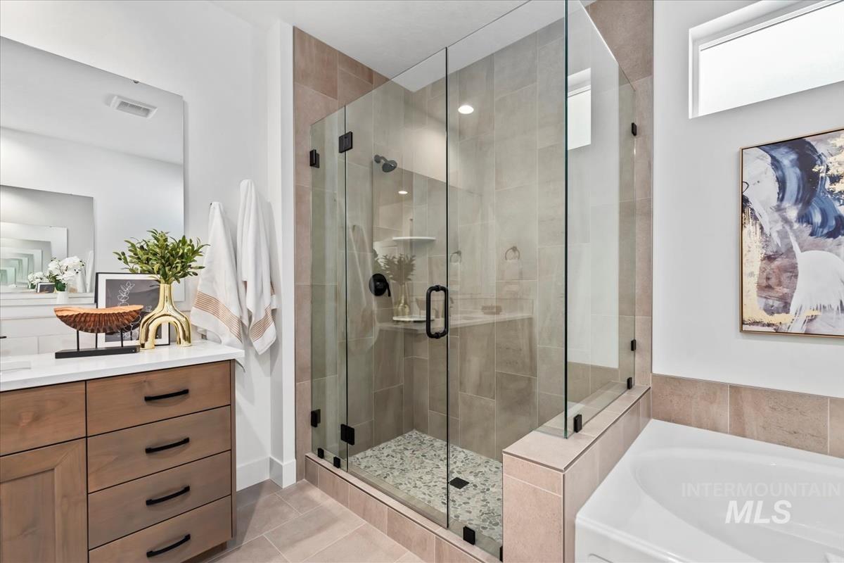 Full bathroom with a shower stall, light tile patterned floors, a bath, and vanity