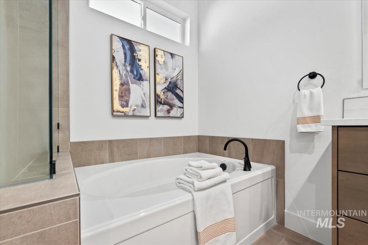 Bathroom with a bath, vanity, and light tile patterned floors