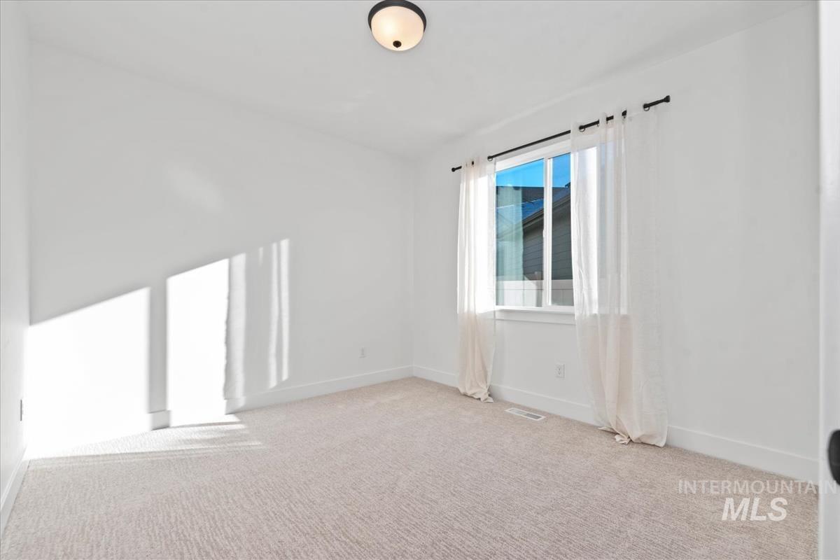 Spare room with light carpet and baseboards