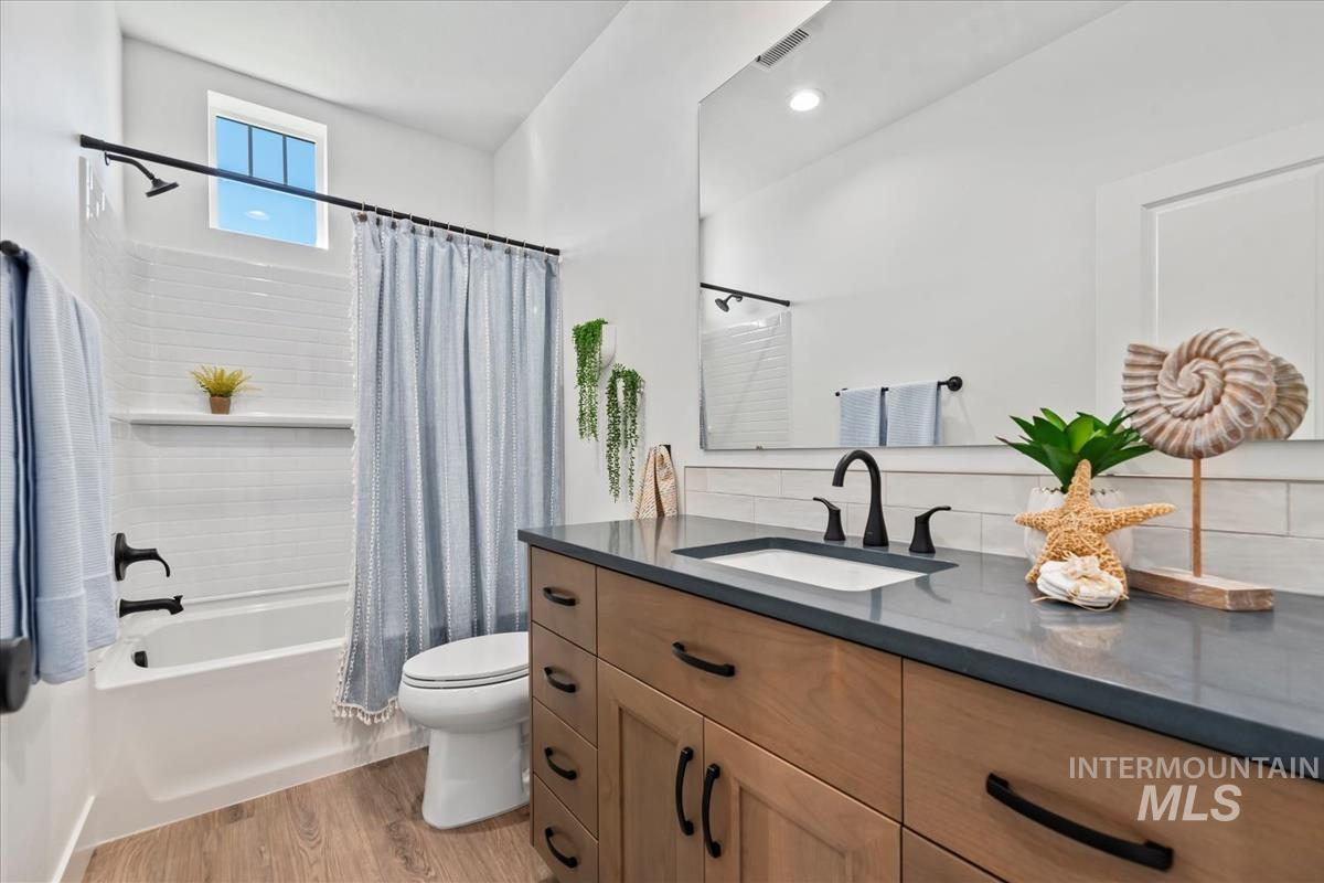 Full bathroom featuring light wood-type flooring, vanity, and shower / tub combo