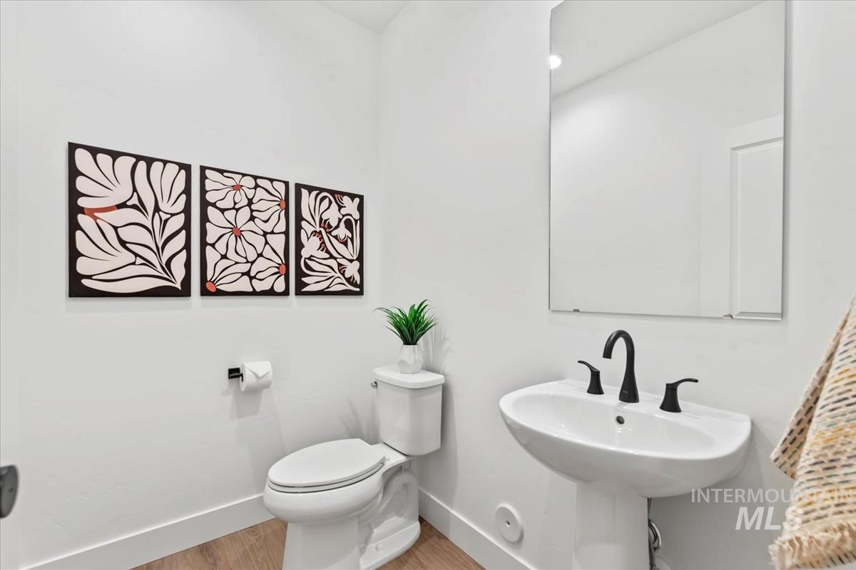 Half bath featuring baseboards and wood finished floors