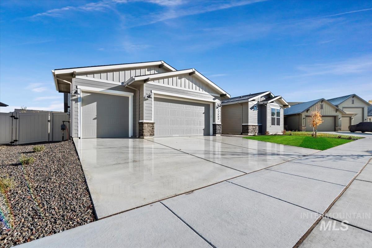 Craftsman inspired home featuring a gate, driveway, board and batten siding, stone siding, and an attached garage