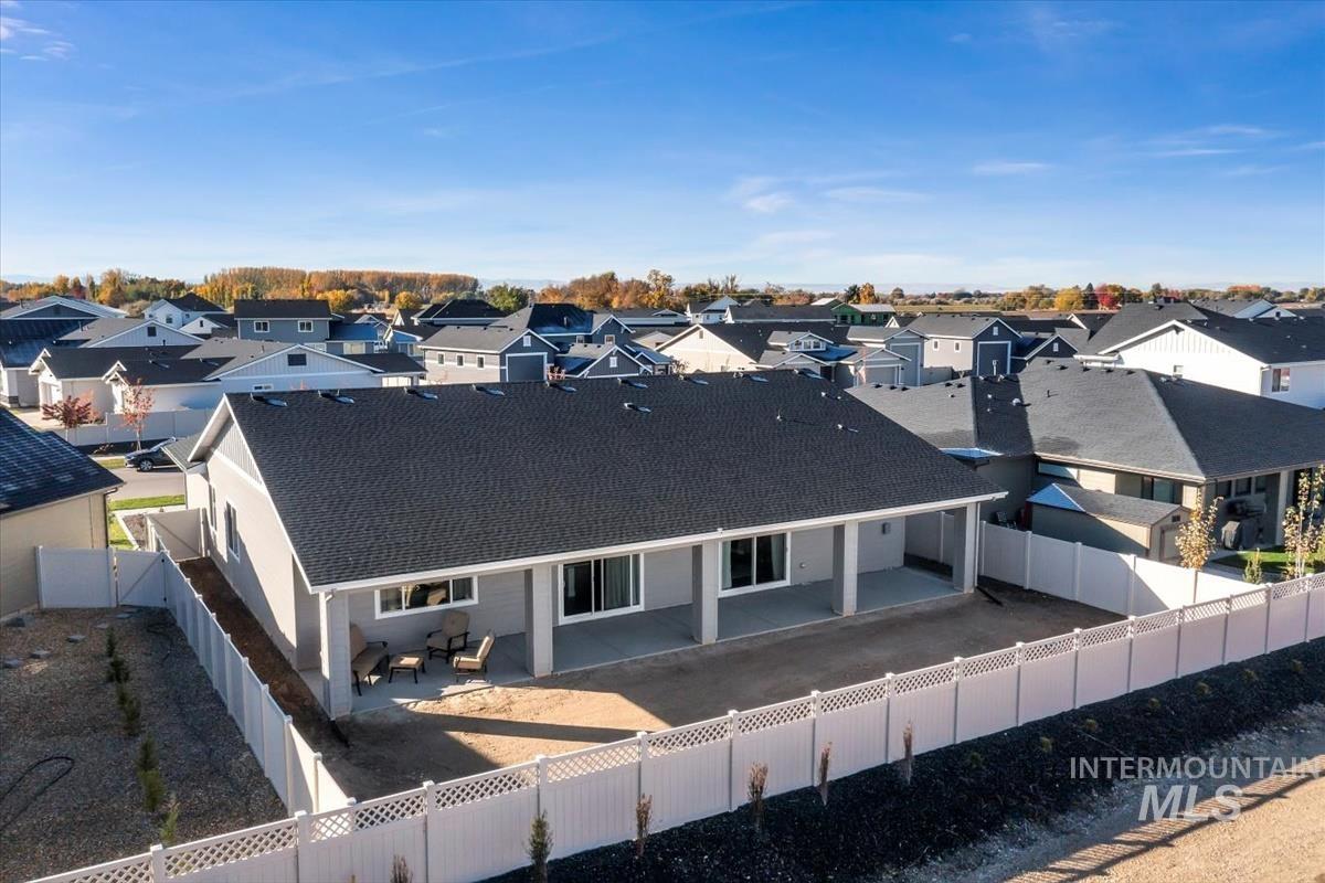 Rear view of house with a patio area, a fenced backyard, a shingled roof, and a residential view