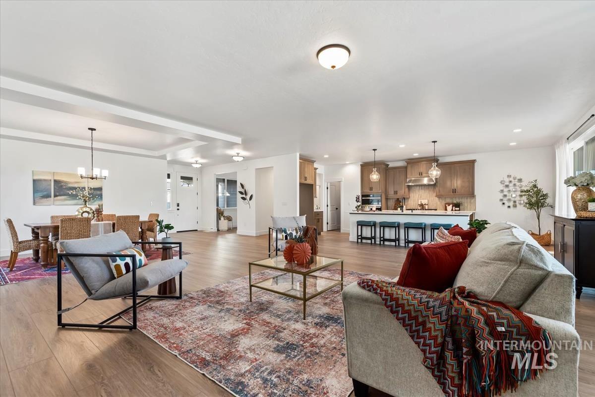Living room with light wood finished floors, a chandelier, and recessed lighting