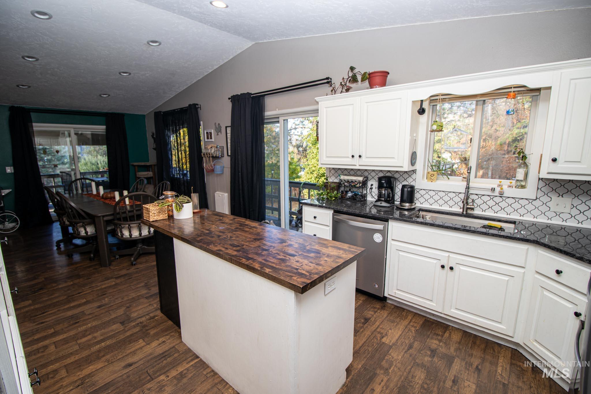 Kitchen with a kitchen island, backsplash, dark wood finished floors, dishwasher, and butcher block countertops
