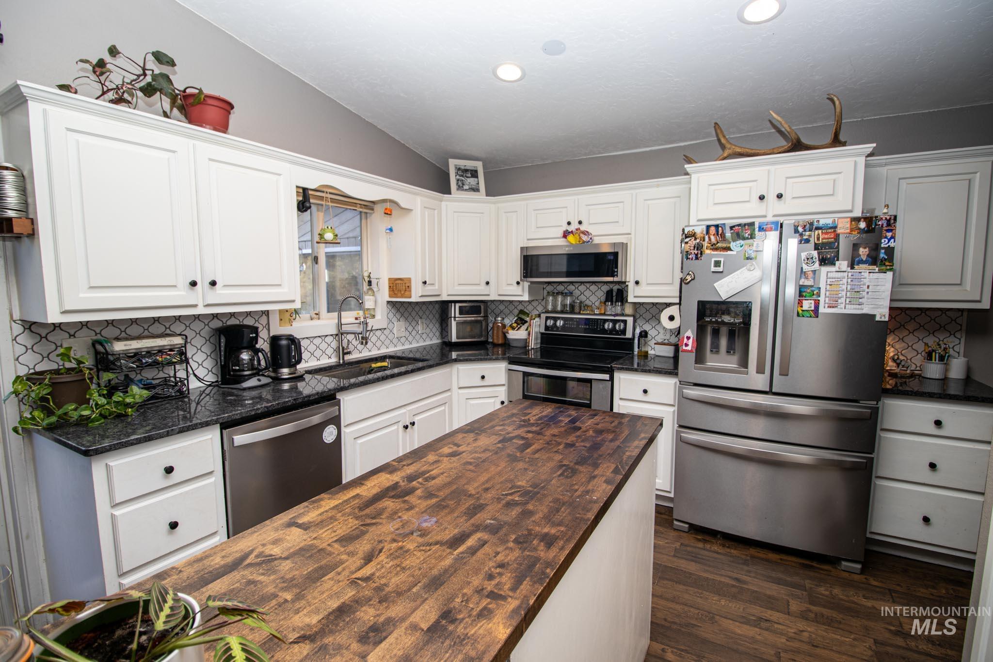 Kitchen featuring stainless steel appliances, wood counters, tasteful backsplash, white cabinets, and recessed lighting
