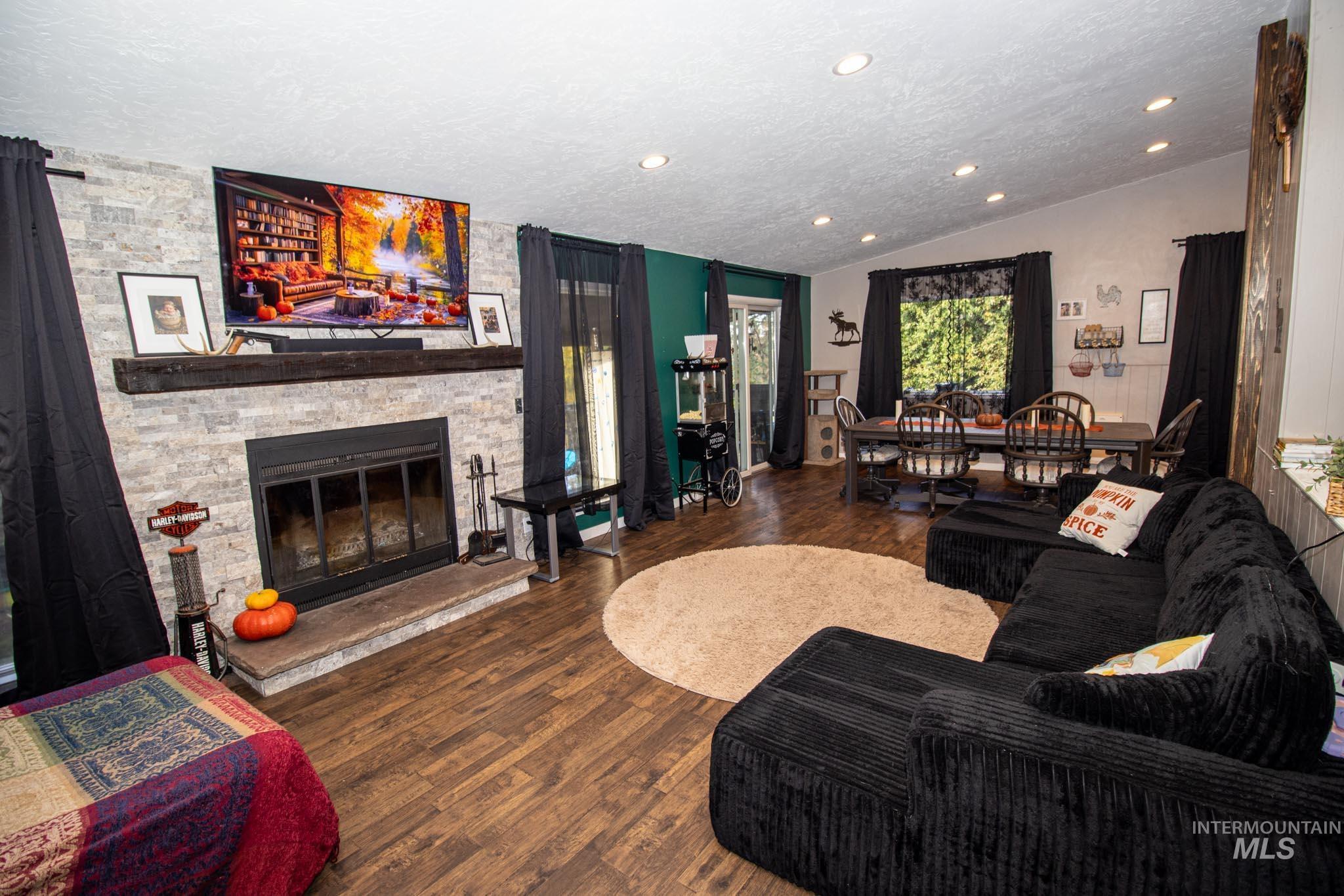 Living room featuring a fireplace, dark wood finished floors, lofted ceiling, a textured ceiling, and recessed lighting