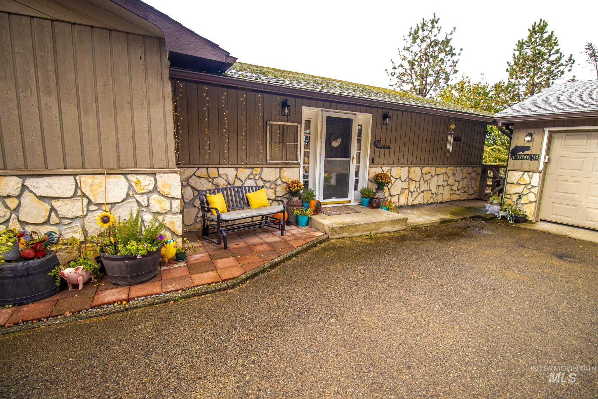 Property entrance with stone siding, a patio, and a shingled roof