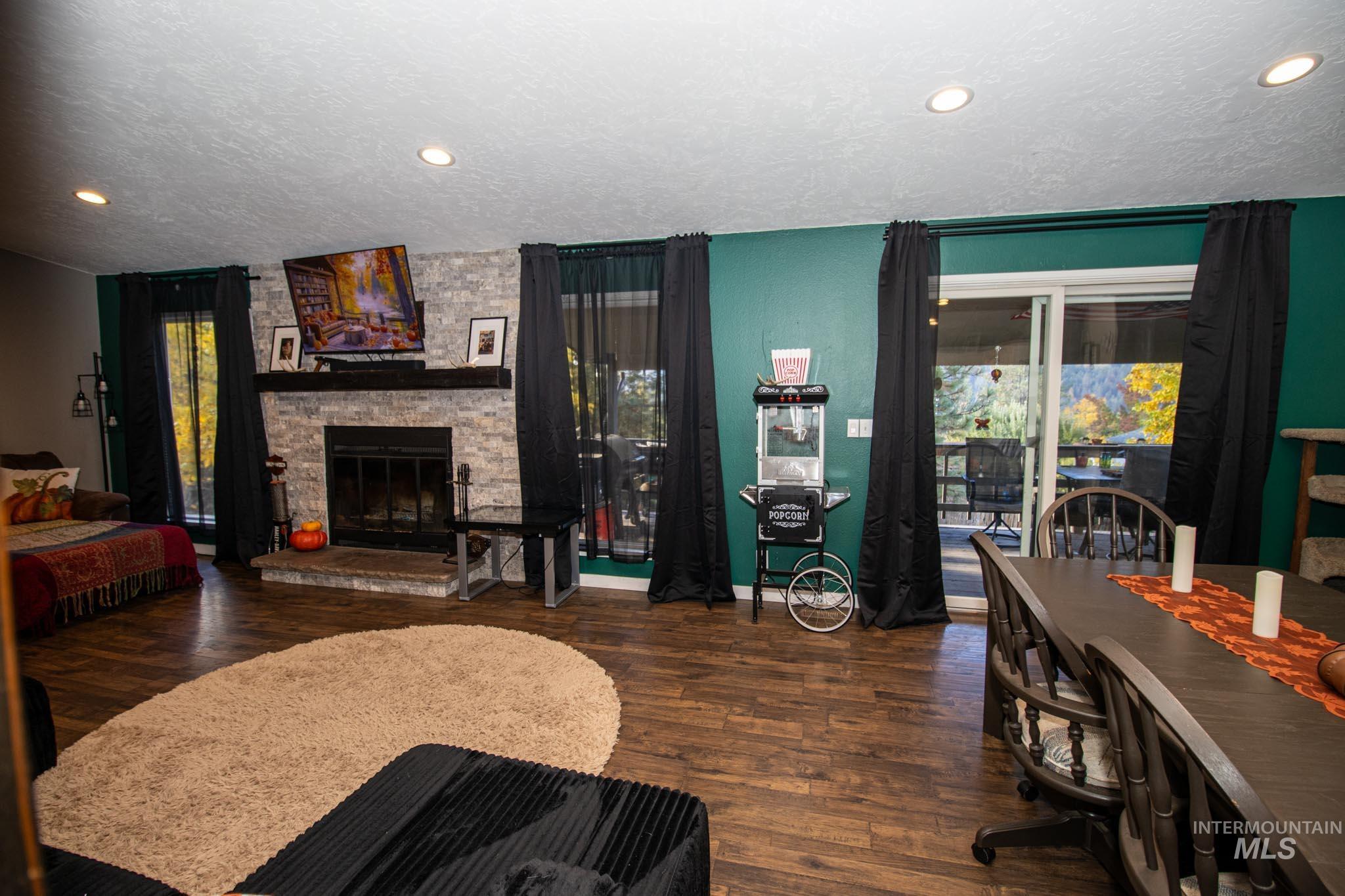 Living area with a textured ceiling, dark wood finished floors, recessed lighting, and a stone fireplace