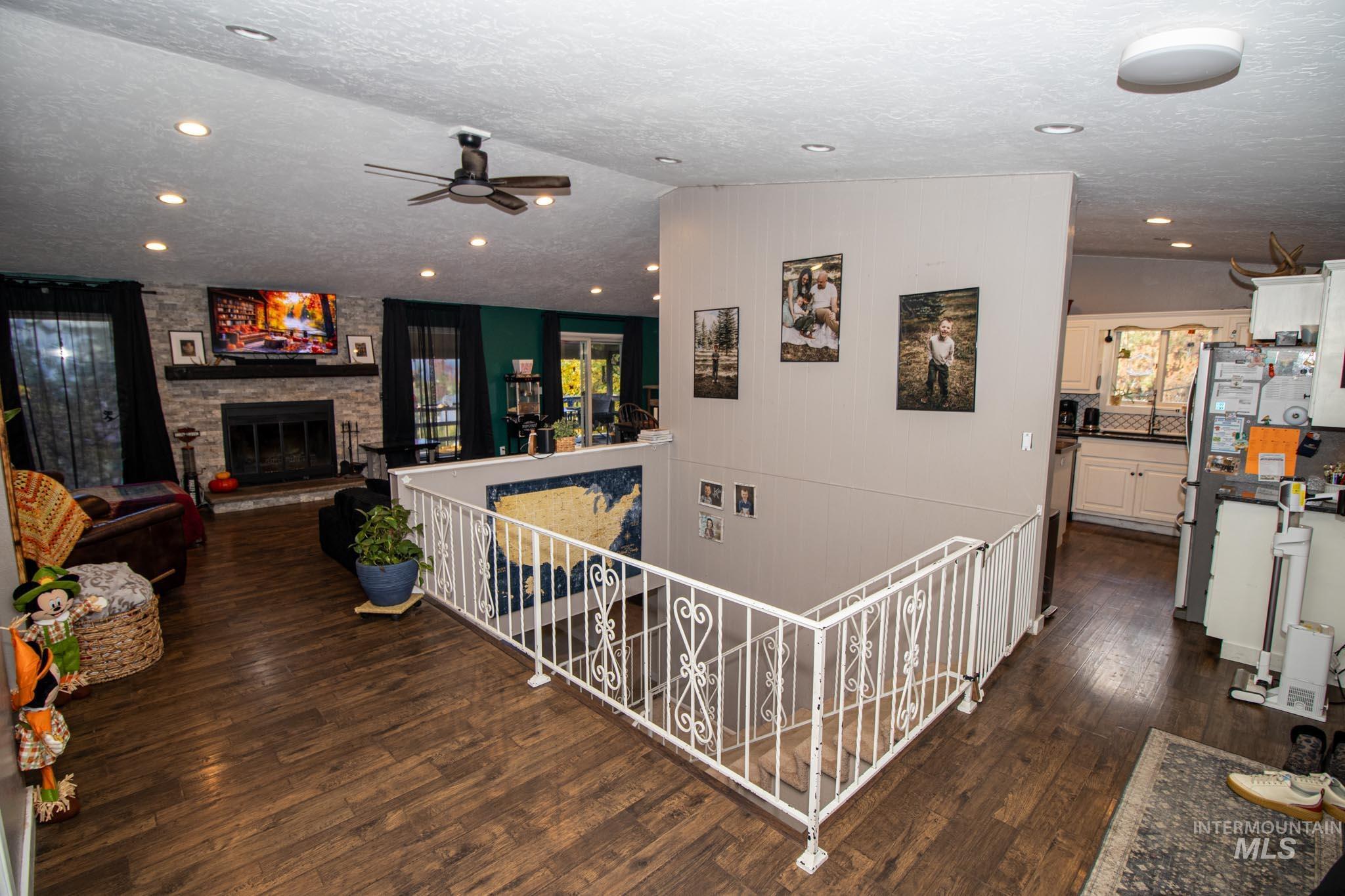Hallway featuring an upstairs landing, dark wood finished floors, a textured ceiling, vaulted ceiling, and recessed lighting