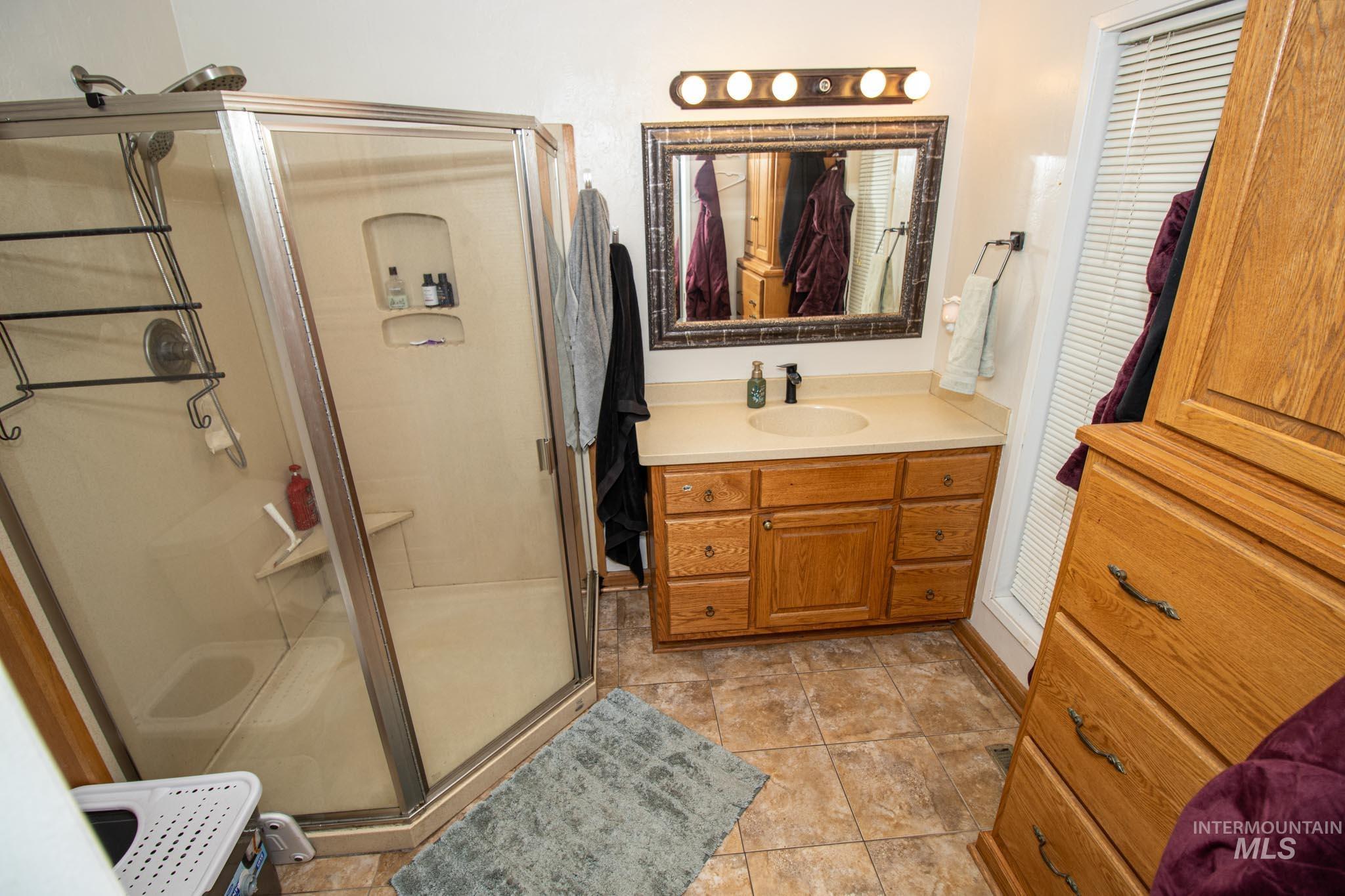 Bathroom with vanity, a stall shower, and light tile patterned flooring
