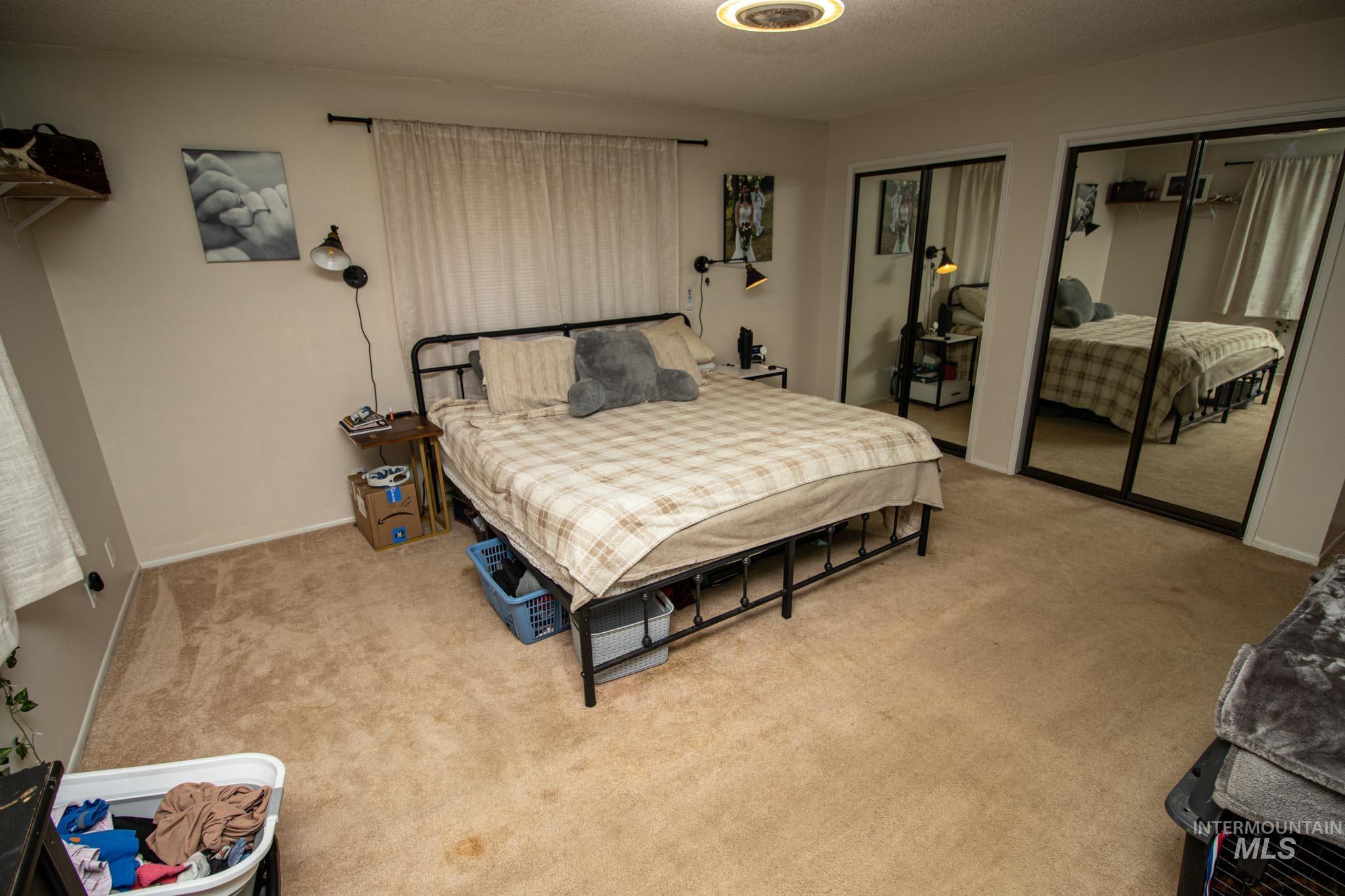 Bedroom with multiple closets, a textured ceiling, and light colored carpet
