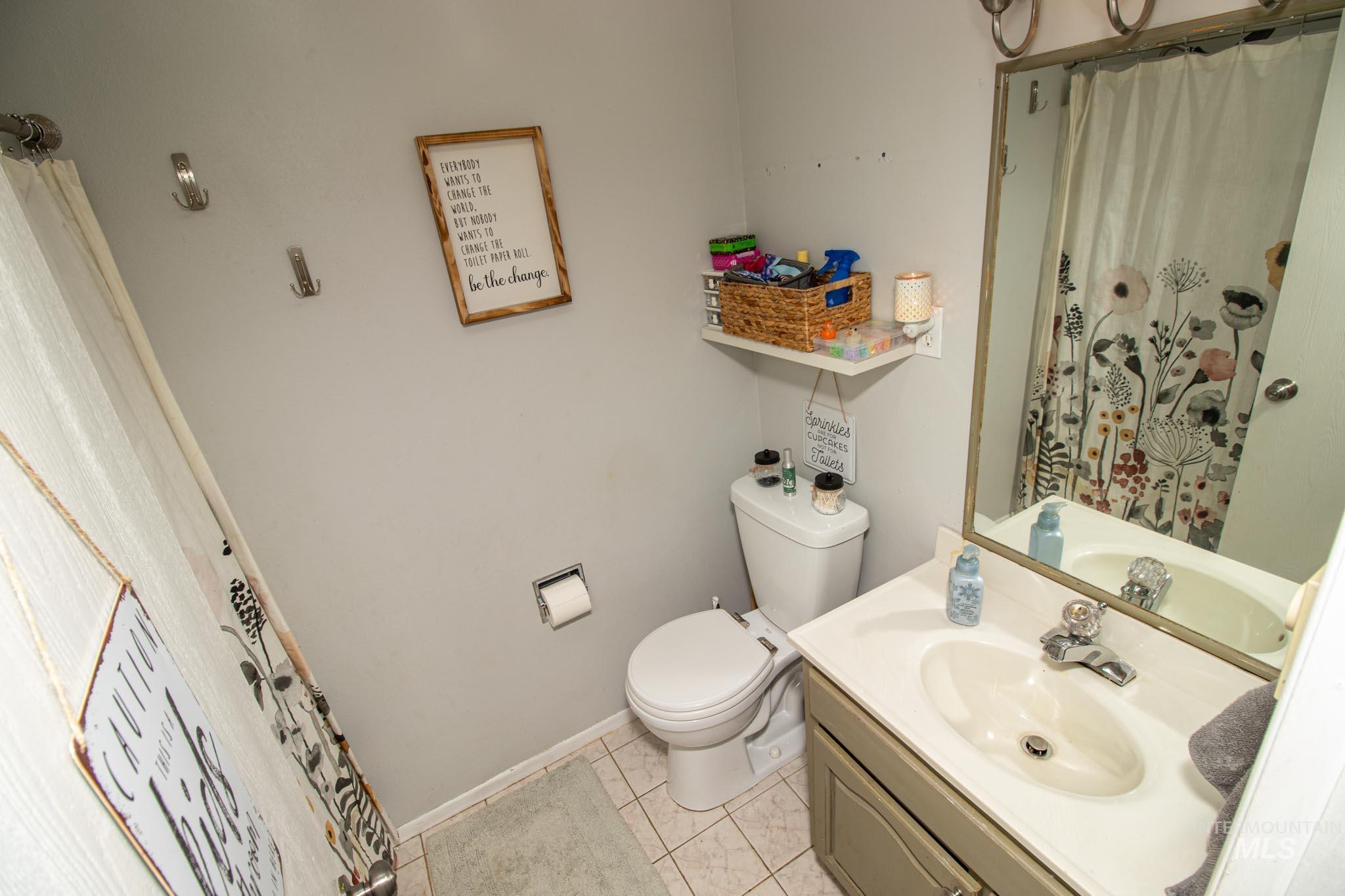 Bathroom with curtained shower, vanity, and light tile patterned floors