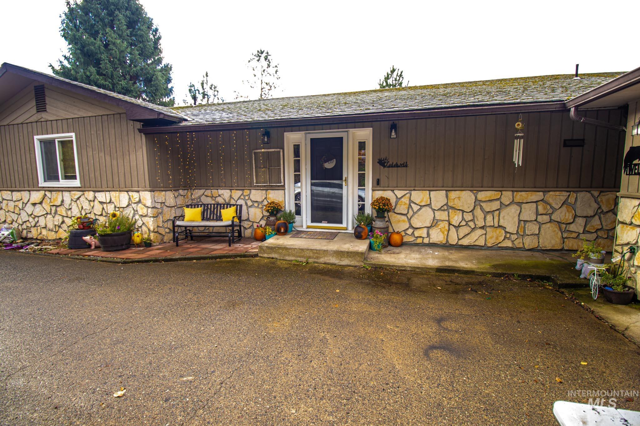 View of exterior entry featuring stone siding, a patio area, and a shingled roof