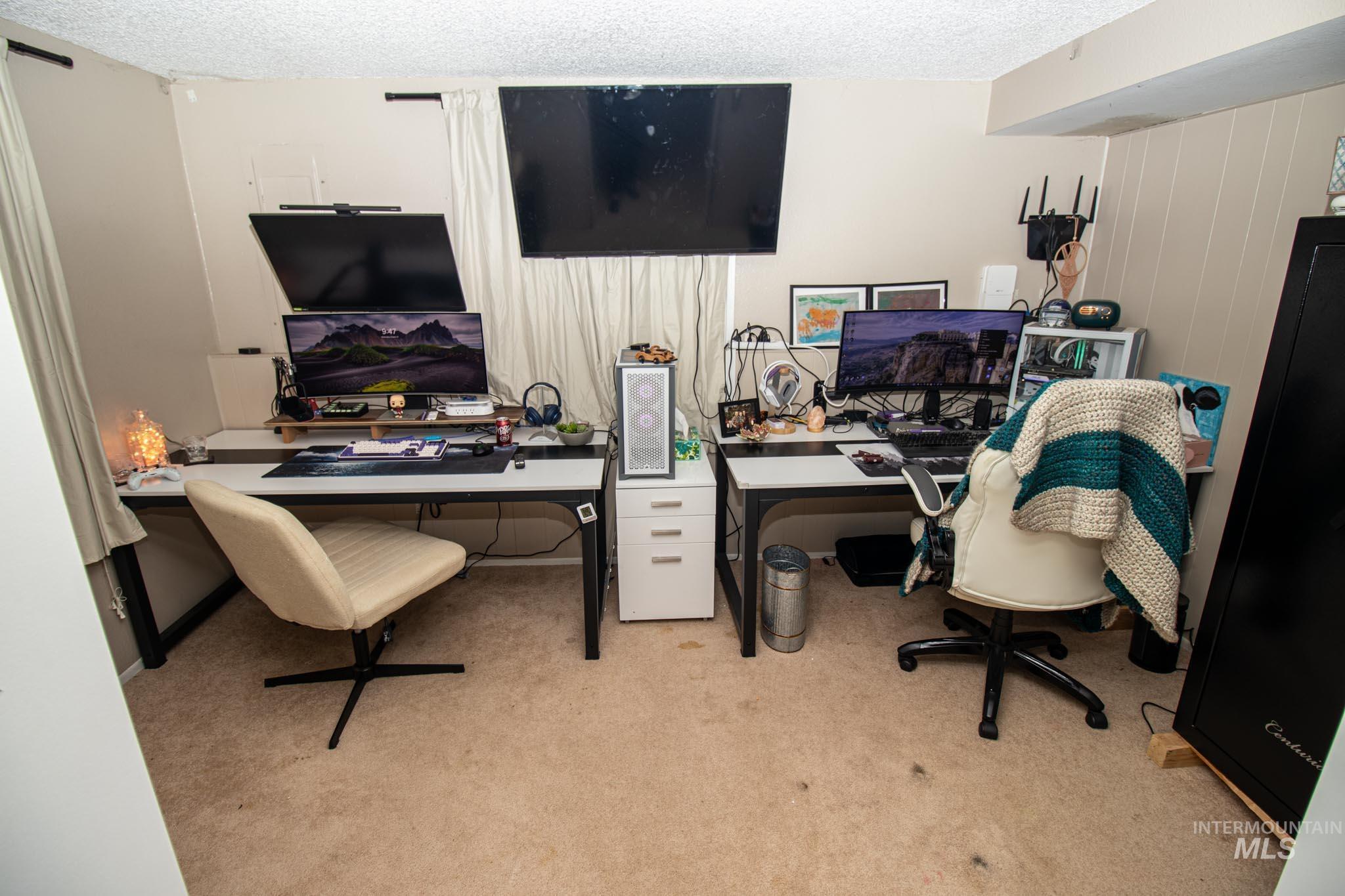 Office space with a textured ceiling and light colored carpet