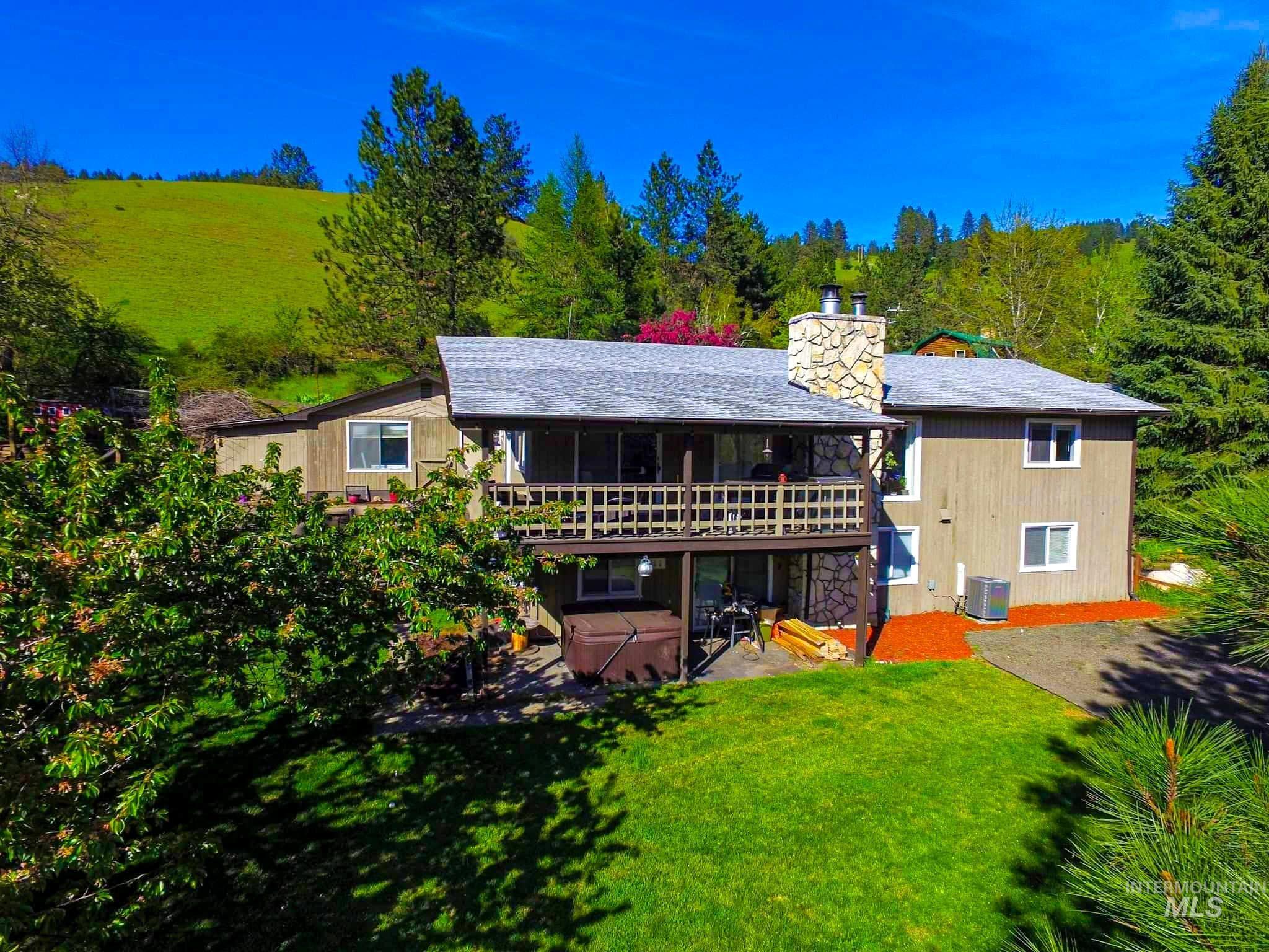 Rear view of property with a yard, a hot tub, a chimney, a patio area, and a balcony