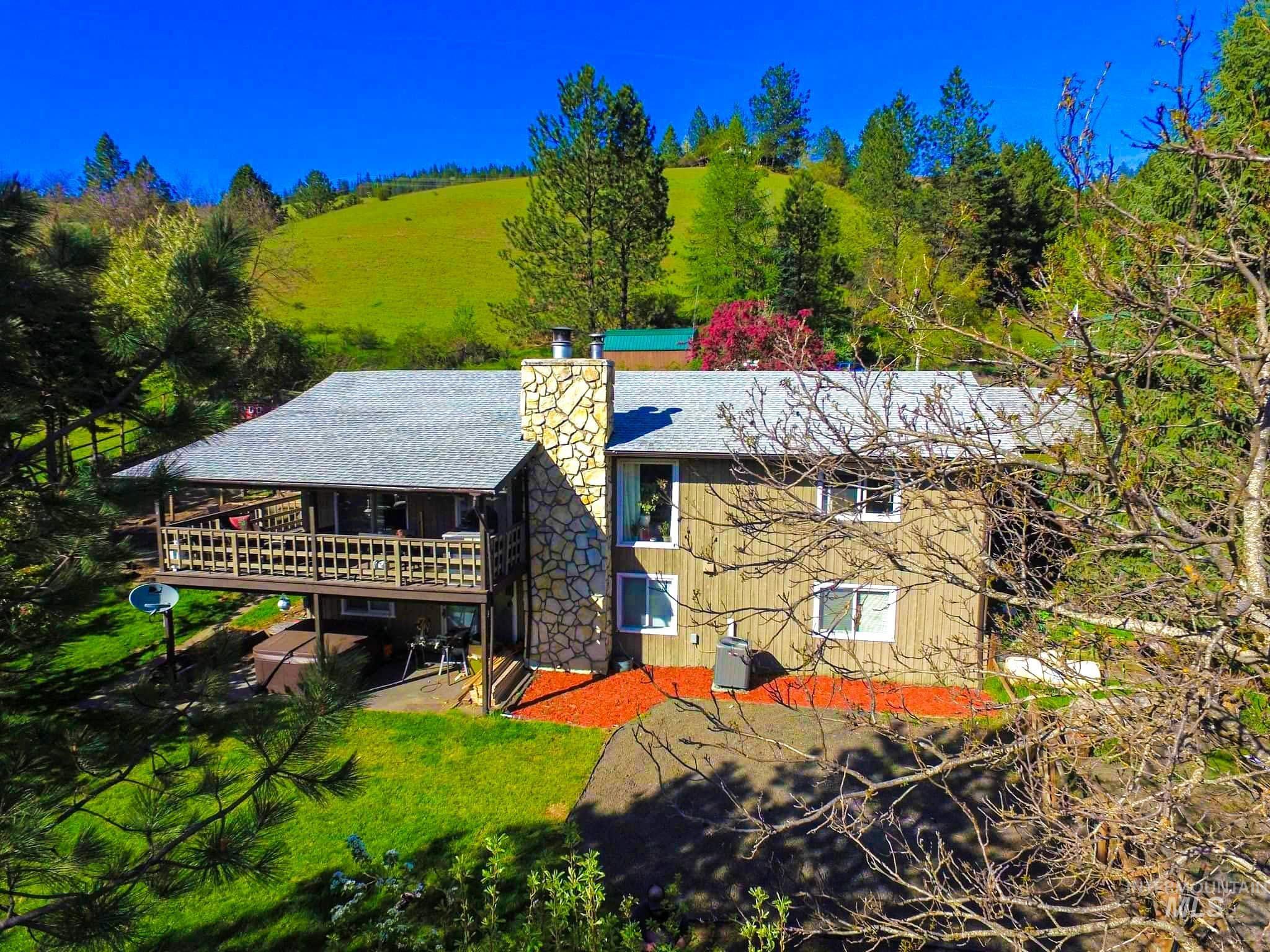 Rear view of house featuring a chimney, a deck, and a yard