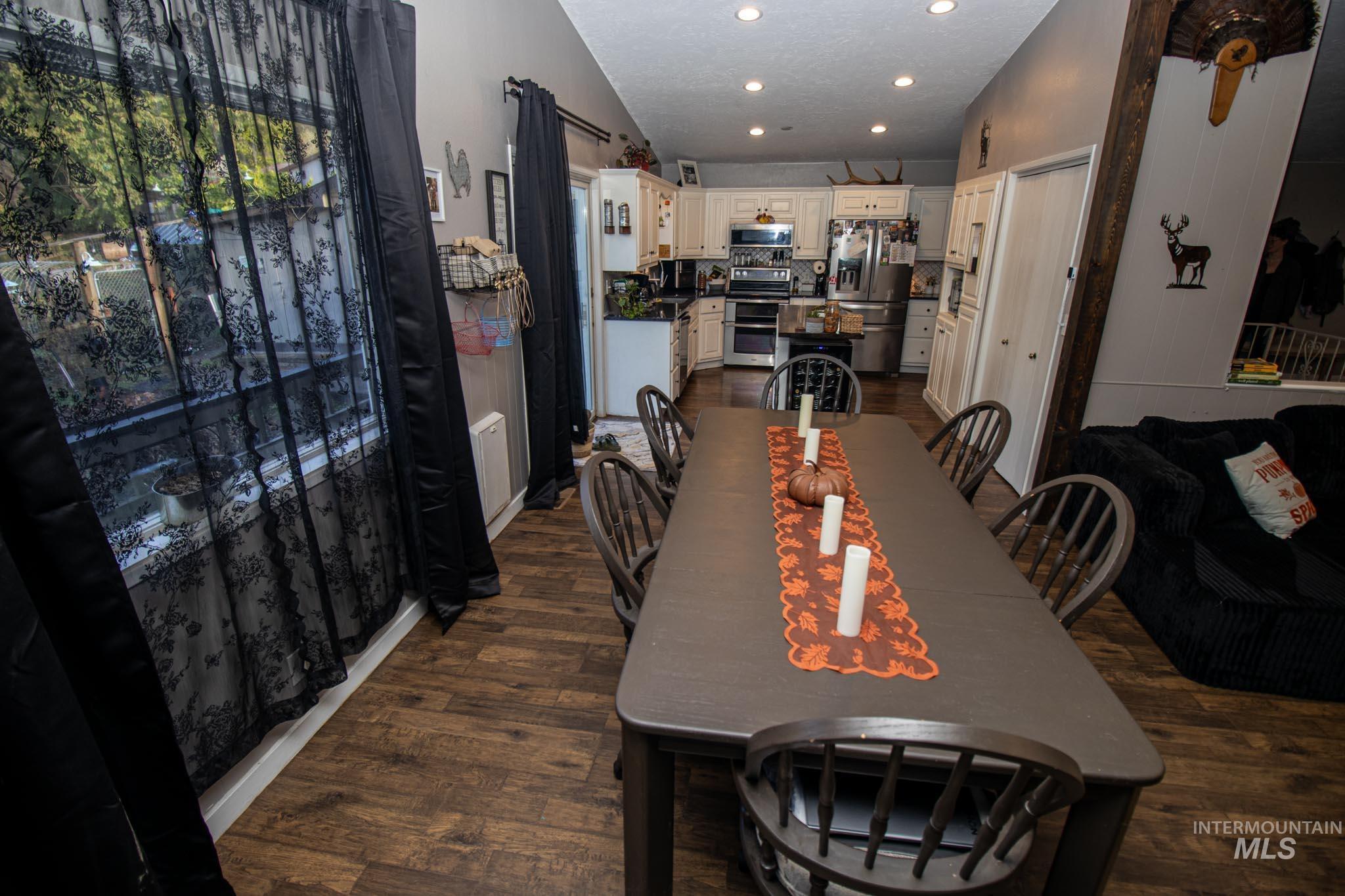 Dining area featuring dark wood-style flooring, a textured ceiling, lofted ceiling, and recessed lighting