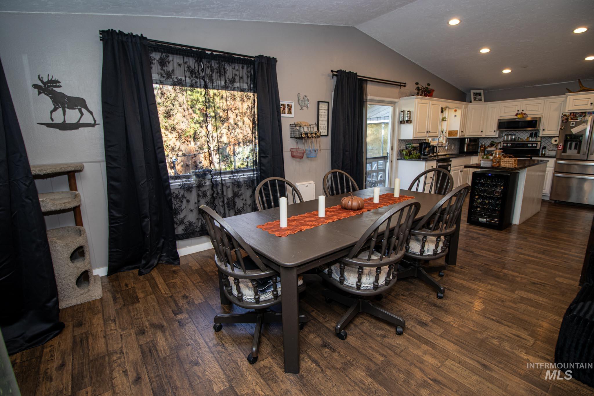 Dining area with dark wood-style flooring, wine cooler, lofted ceiling, recessed lighting, and a textured ceiling