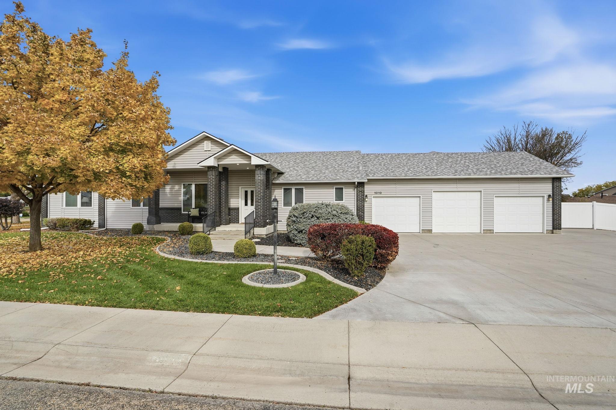 Ranch-style house featuring roof with shingles, concrete driveway, a front yard, and an attached garage
