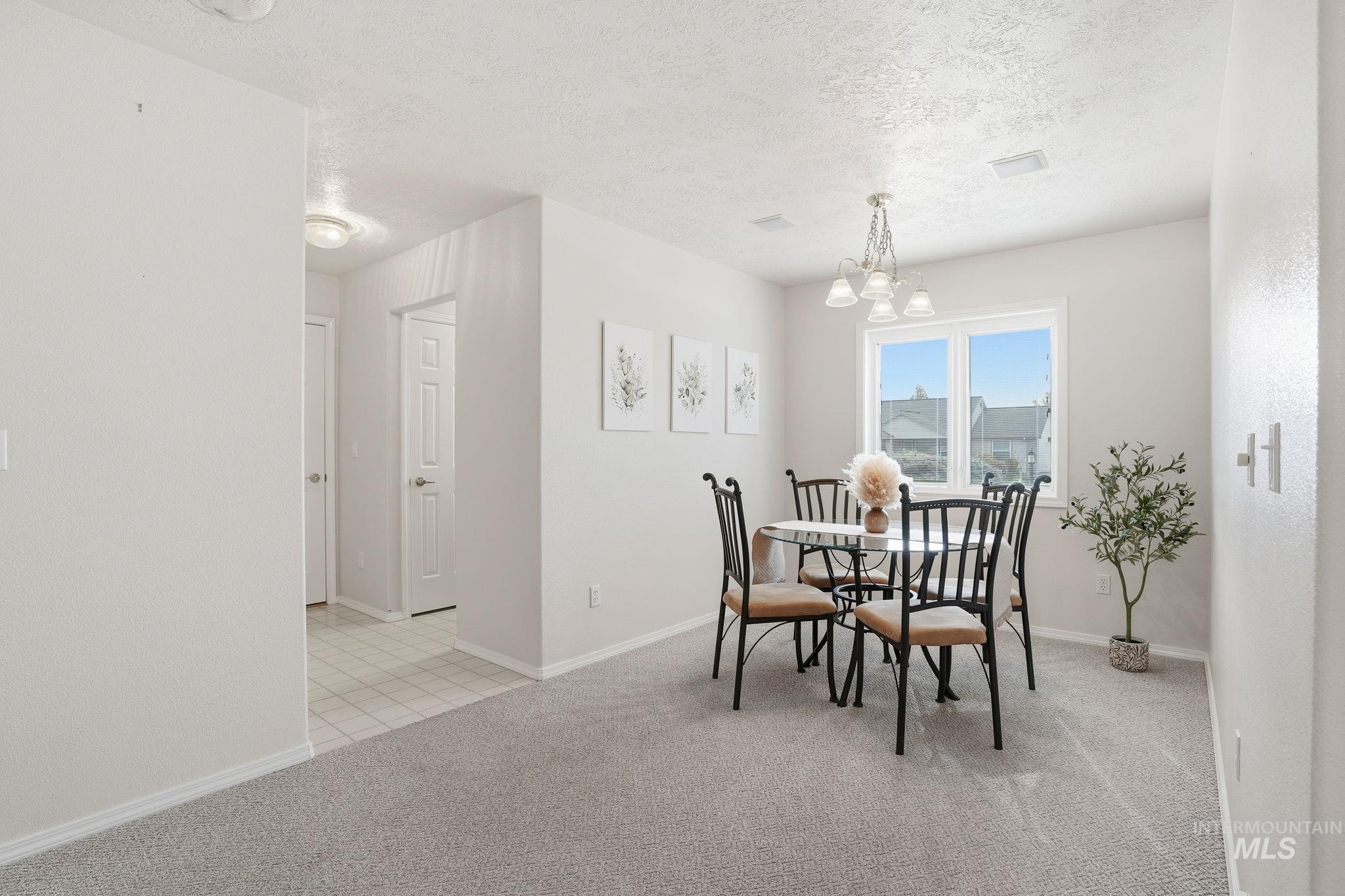 Dining room with light colored carpet, a textured ceiling, and a chandelier