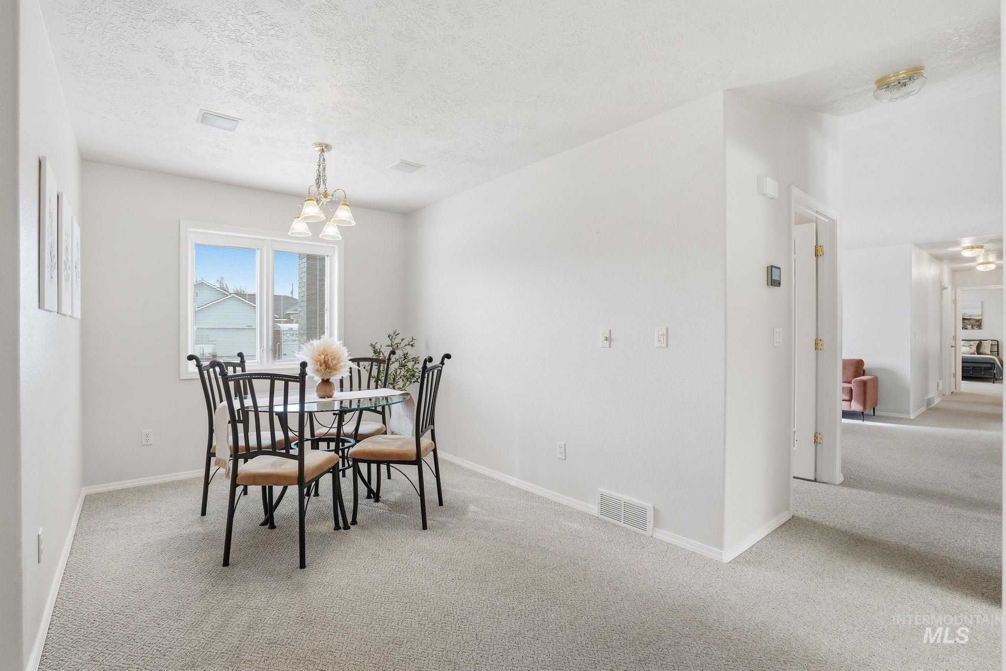 Dining room featuring carpet floors, a textured ceiling, and a chandelier