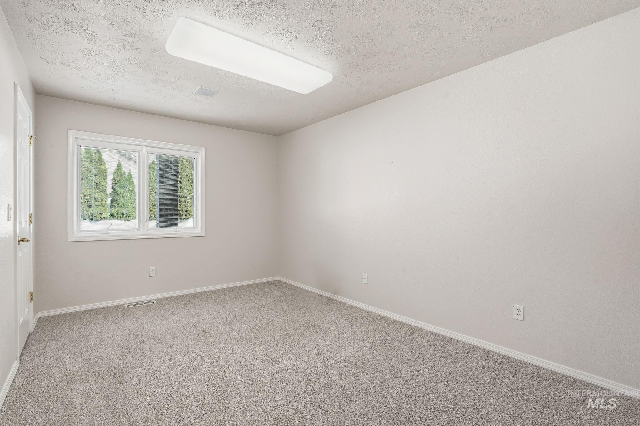 Bedroom #2 featuring light colored carpet and a textured ceiling and walk-in closet