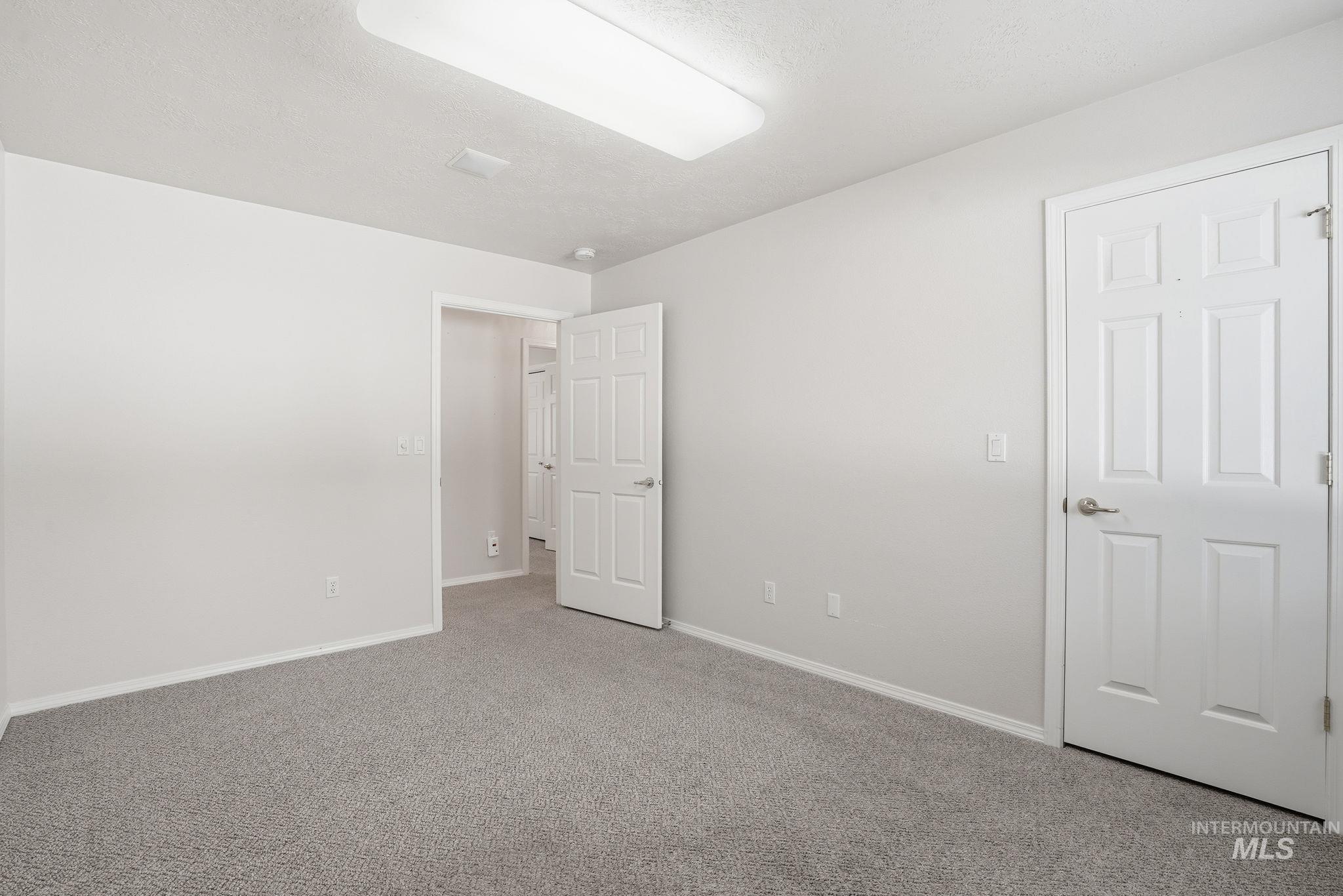 Bedroom #2 featuring light colored carpet and a textured ceiling and walk-in closet