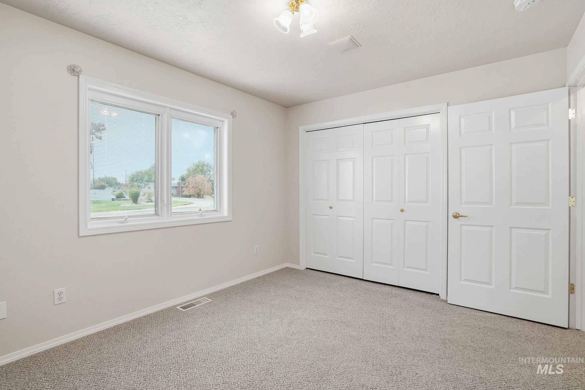 Bedroom #3 with light colored carpet, a large closet, and a textured ceiling