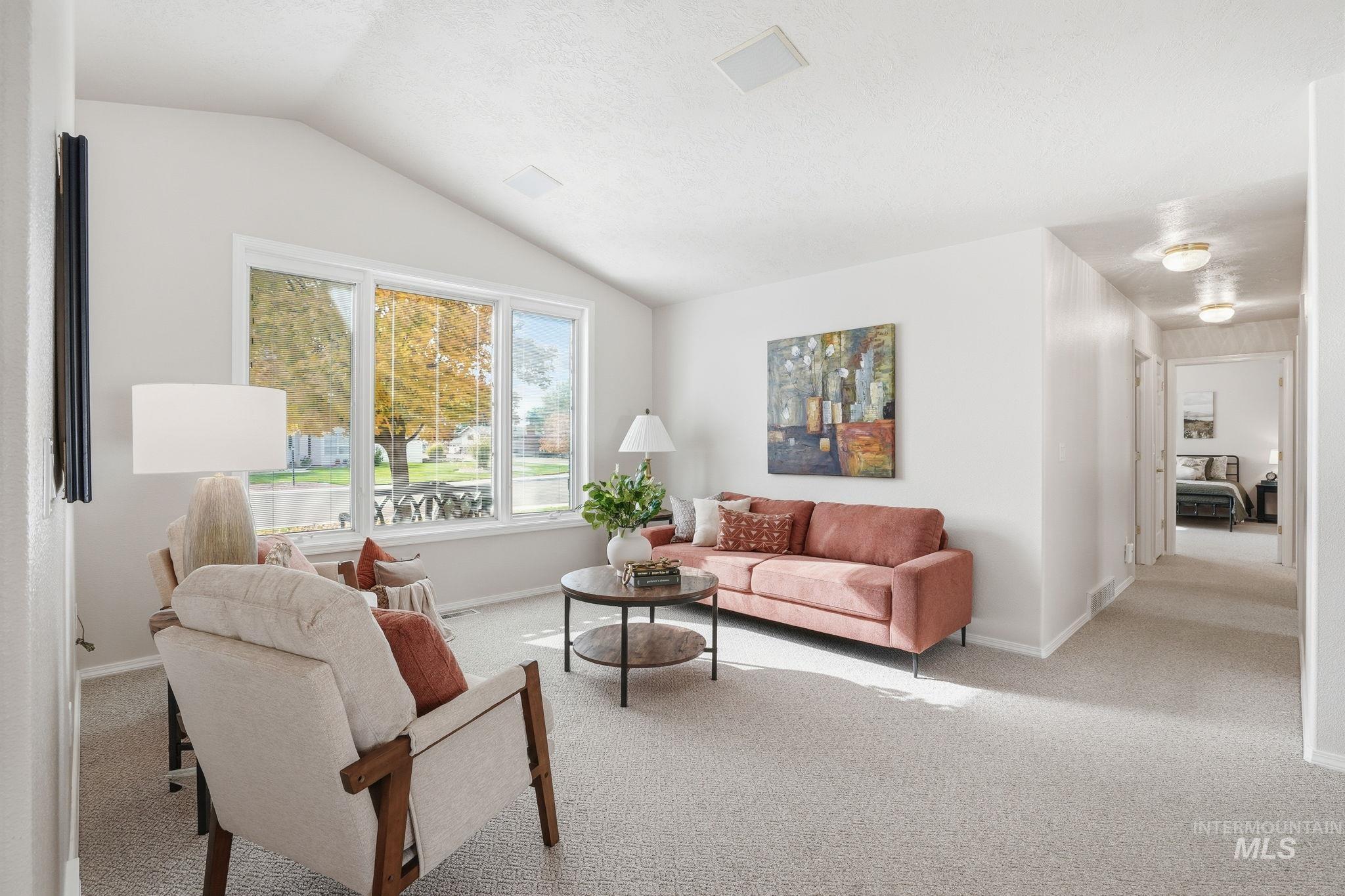Carpeted living area featuring lofted ceiling and baseboards