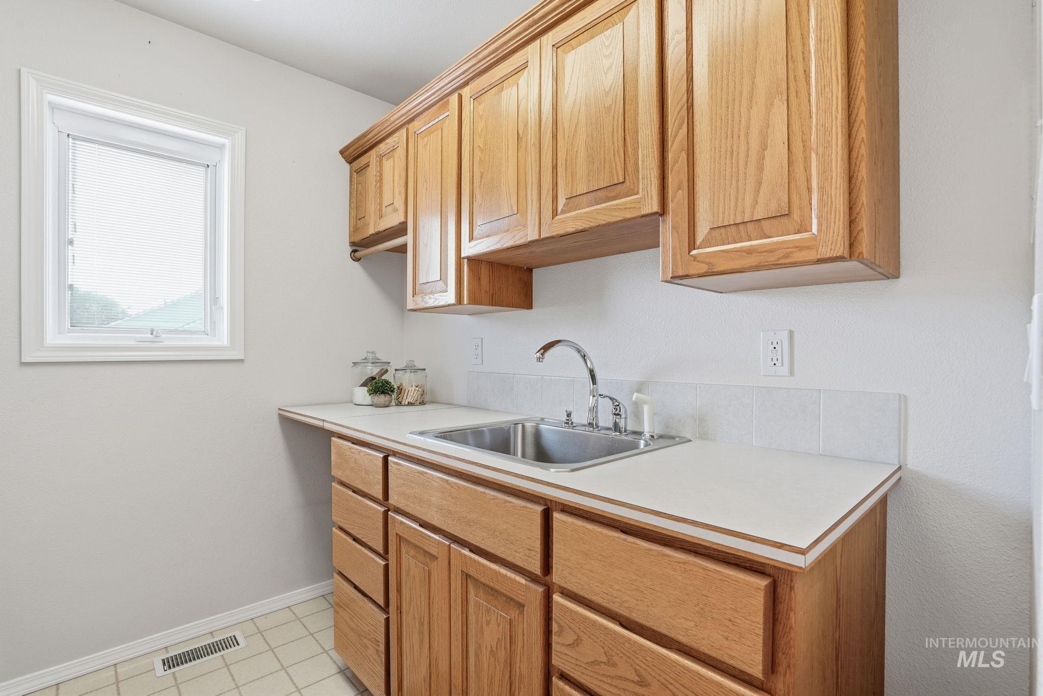 Laundry Room featuring light countertops, sink, folding area and light tile patterned floors
