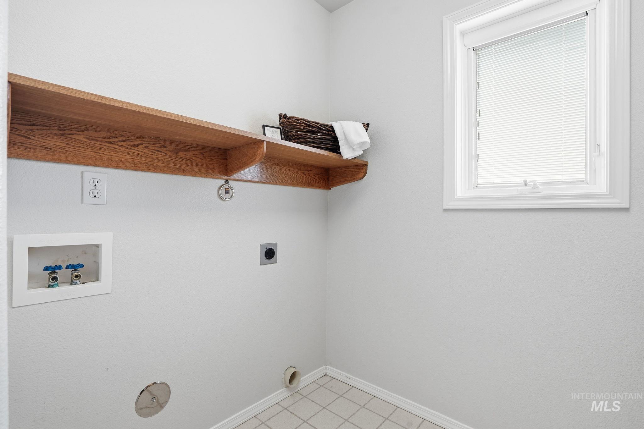 Laundry room featuring washer and dryer hookup, light tile patterned floors, a folding area and extra storage under the counter