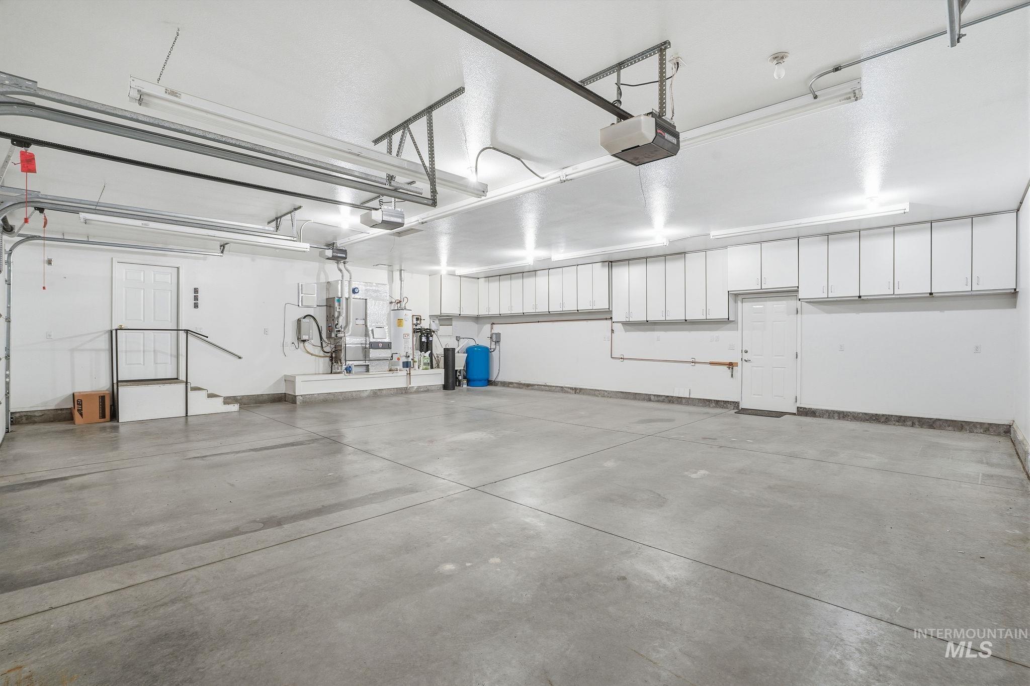 Garage featuring heating unit, water heater, and a garage door opener